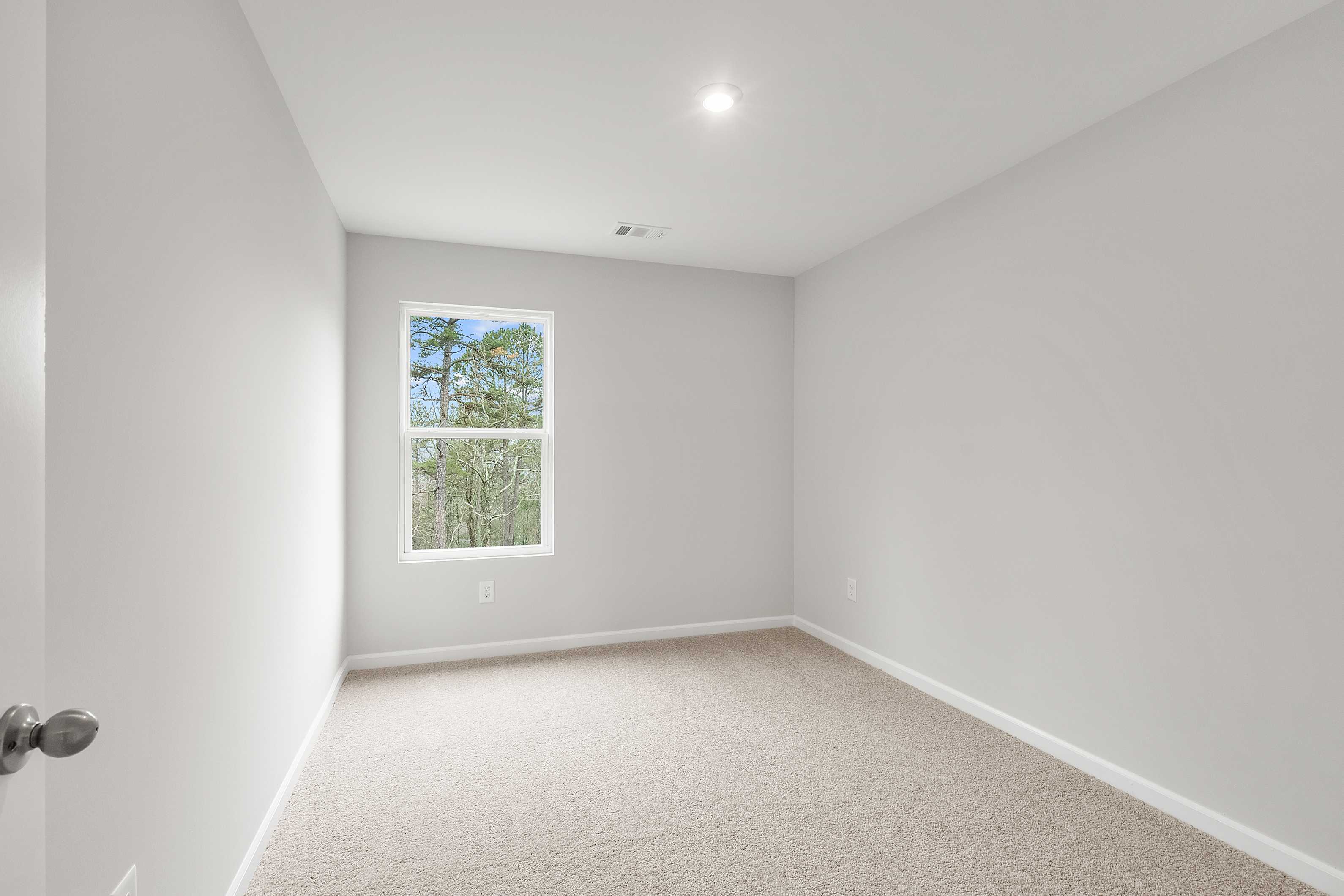 Upper floor bedroom in The Durant A with light gray walls, neutral carpet, and double window overlooking pine trees