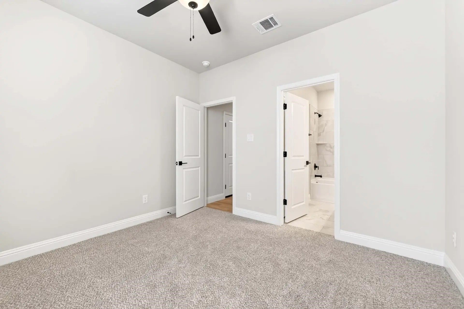 Spacious bedroom with plush carpet and ensuite bathroom in The Holly C floor plan by Davidson Homes in Heartland, Texas.