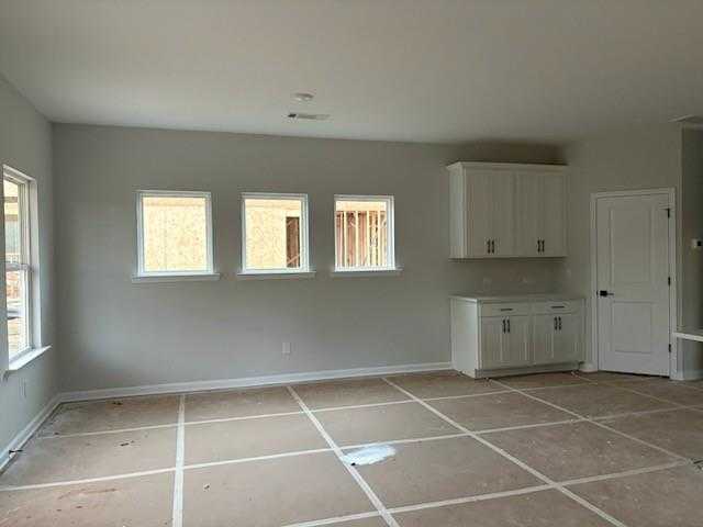 Unfinished modern kitchen with white cabinets, gray walls, three windows, and plywood flooring in Davidson Homes The Rabun C, Winder, GA