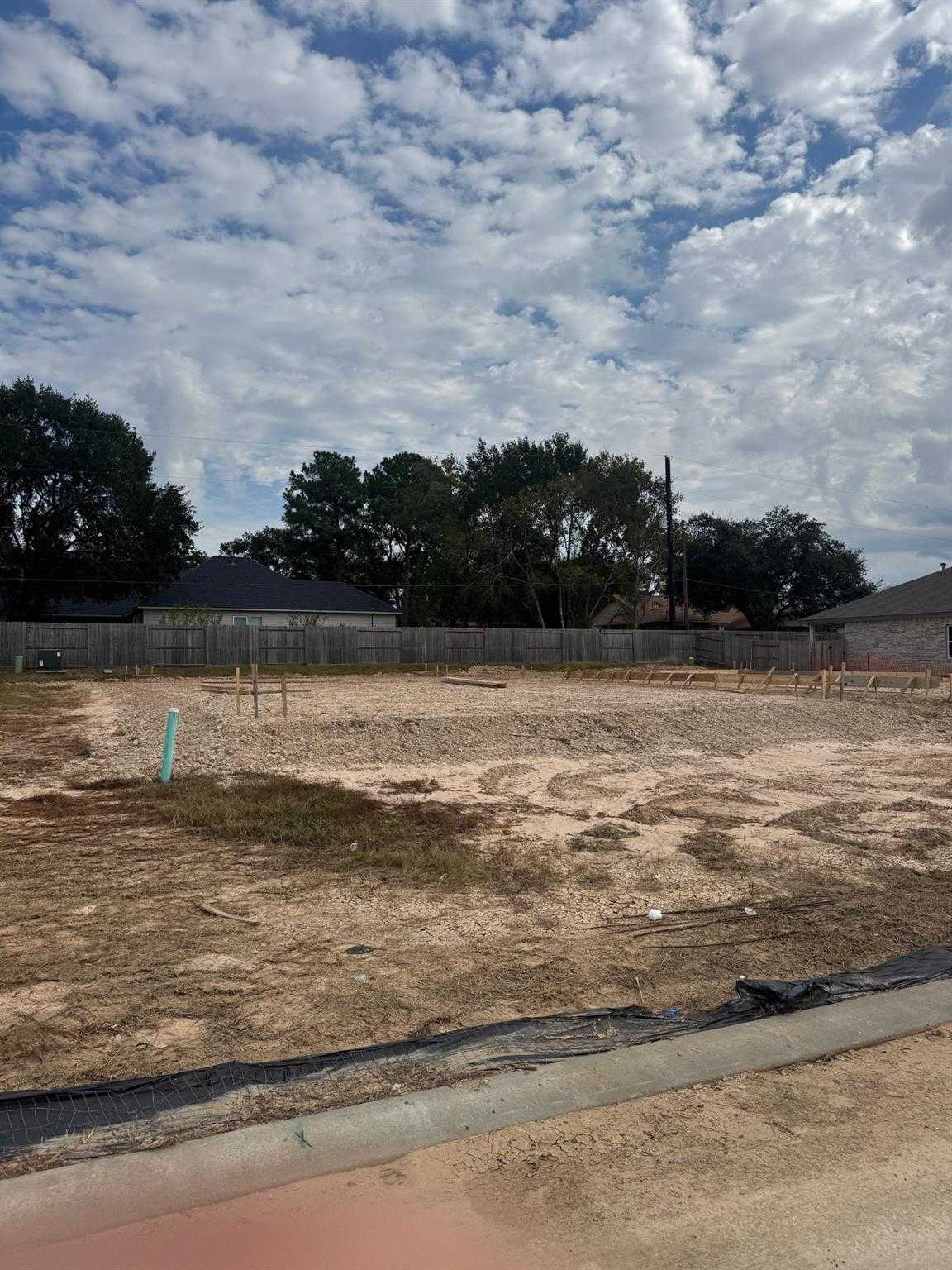 Cleared lot with wooden fencing, green stakes, and dirt ground for Davidson Homes Blanco E in Windmill Estates, Magnolia, Texas