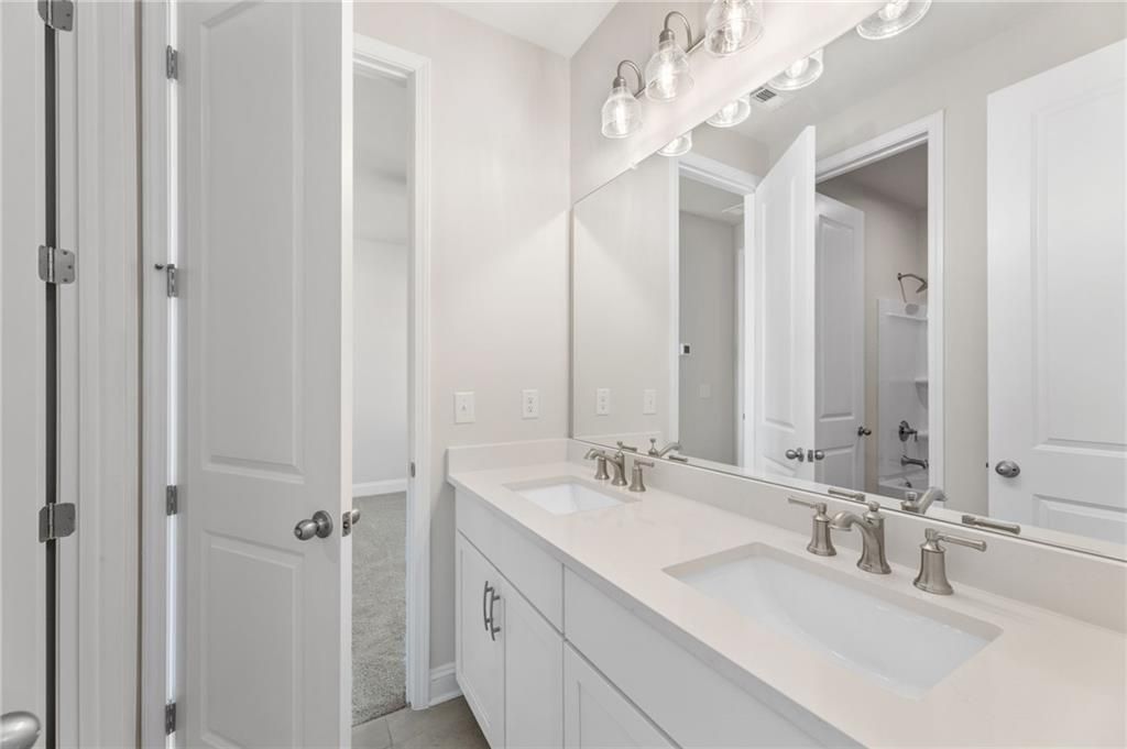 Modern master bathroom with double white quartz vanity, sconce lighting, and open walk-in closet in The Danbury C, Buford, GA