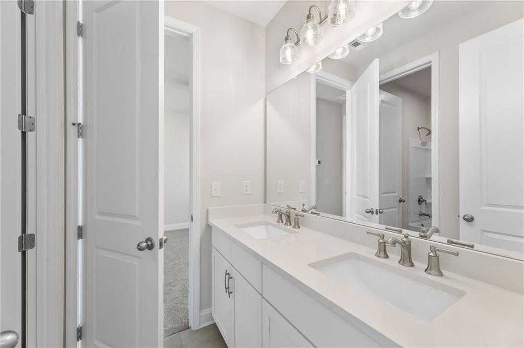 Modern master bathroom with double white quartz vanity, sconce lighting, and open walk-in closet in The Danbury C, Buford, GA
