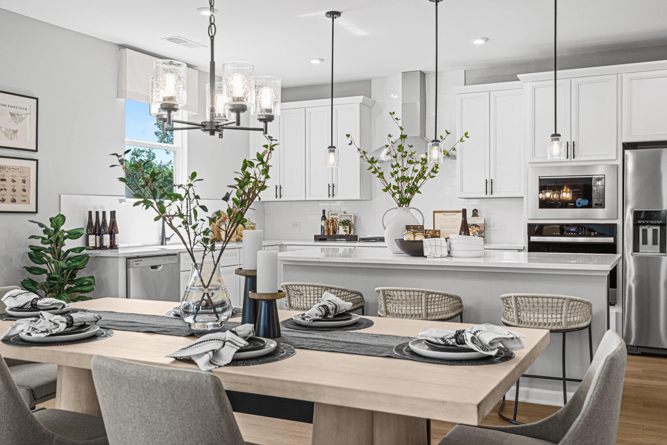 Spacious kitchen in The Hickory B by Davidson Homes with white shaker cabinets, stainless steel appliances, pendant lights, and rattan bar stools