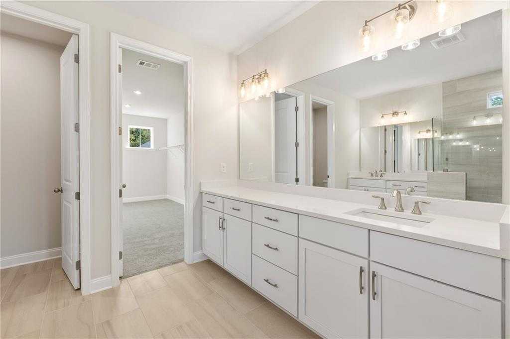 Modern master bathroom with double vanity, white cabinets, large mirror, and tiled backsplash in Davidson Homes The Hampton C, Buford, Georgia