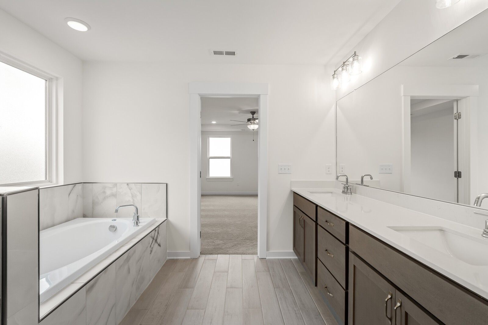 Modern primary bathroom with deep soaking tub, dual vanity, and tile flooring in The Henry C floor plan, Mt. Juliet.