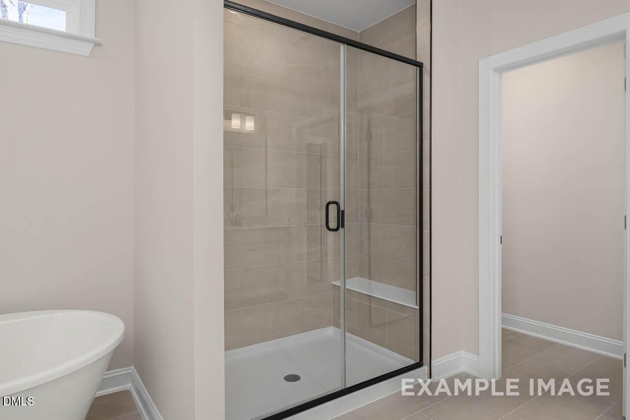 Modern master bathroom featuring frameless glass shower and freestanding tub in Davidson Homes Crawford D, Angier NC
