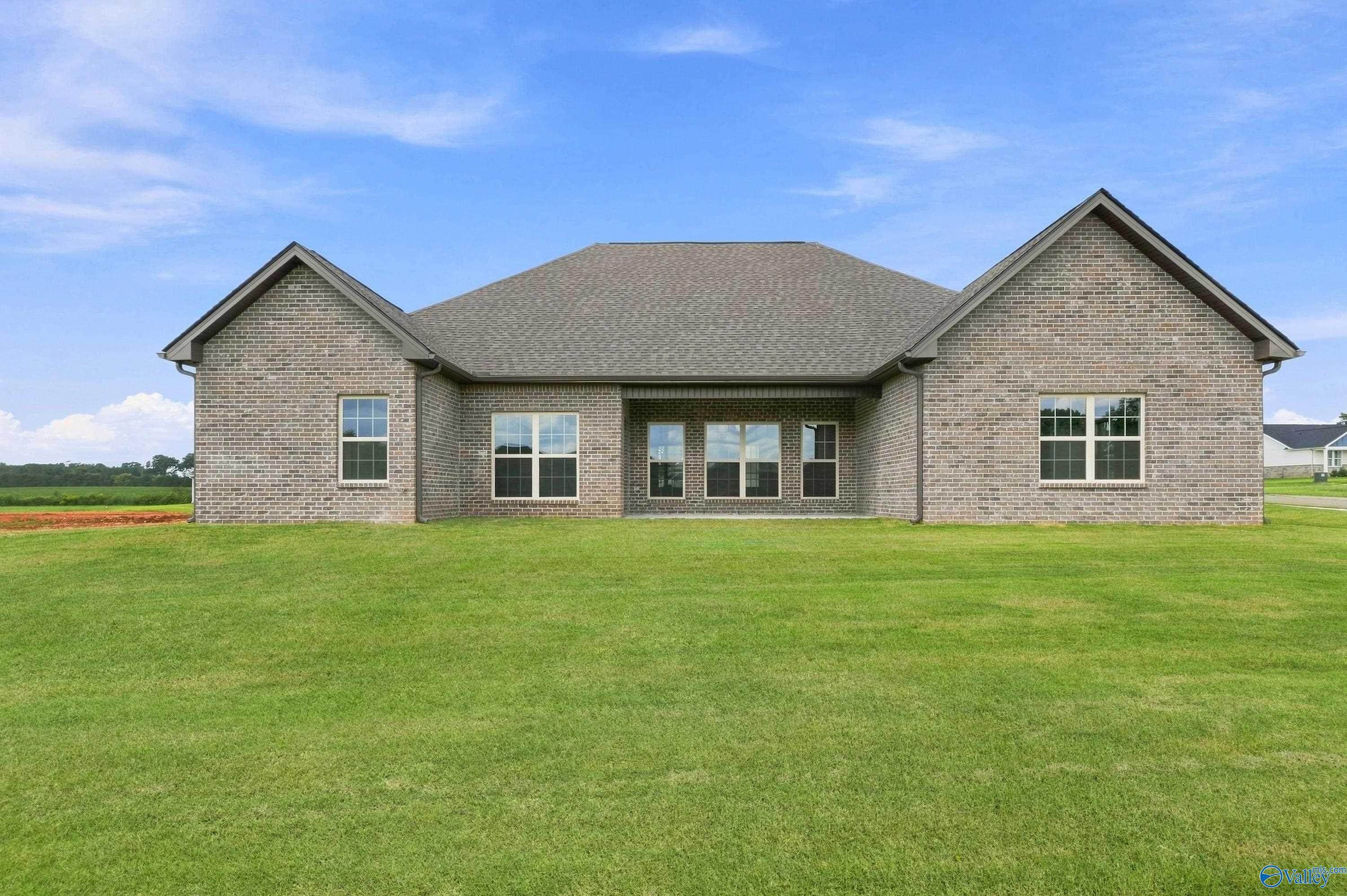 Rear exterior of brick 1-story home with covered patio and spacious backyard in Riverton Preserve, Huntsville, Alabama