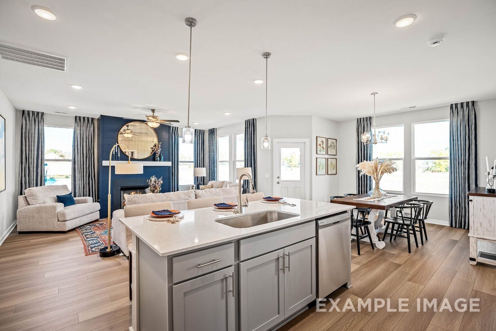 Open-concept living room with blue-tiled fireplace, kitchen island, and dining area in Davidson Homes The Franklin B, White House, TN