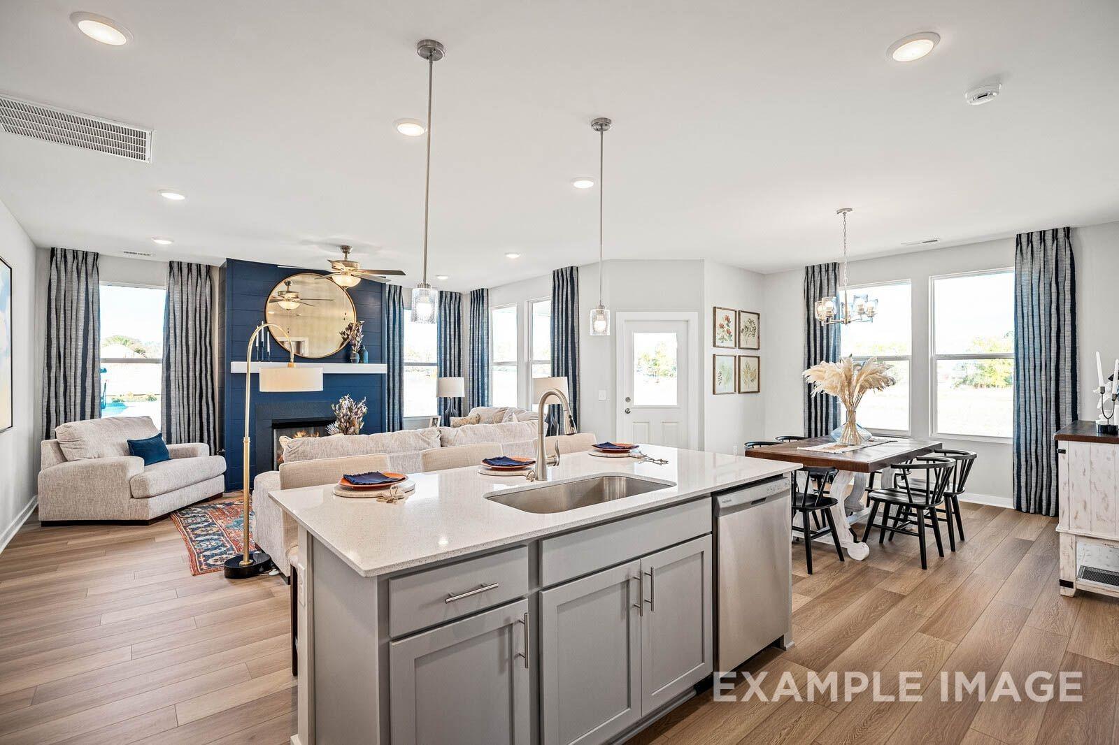 Open-concept living room with blue-tiled fireplace, kitchen island, and dining area in Davidson Homes The Franklin B, White House, TN