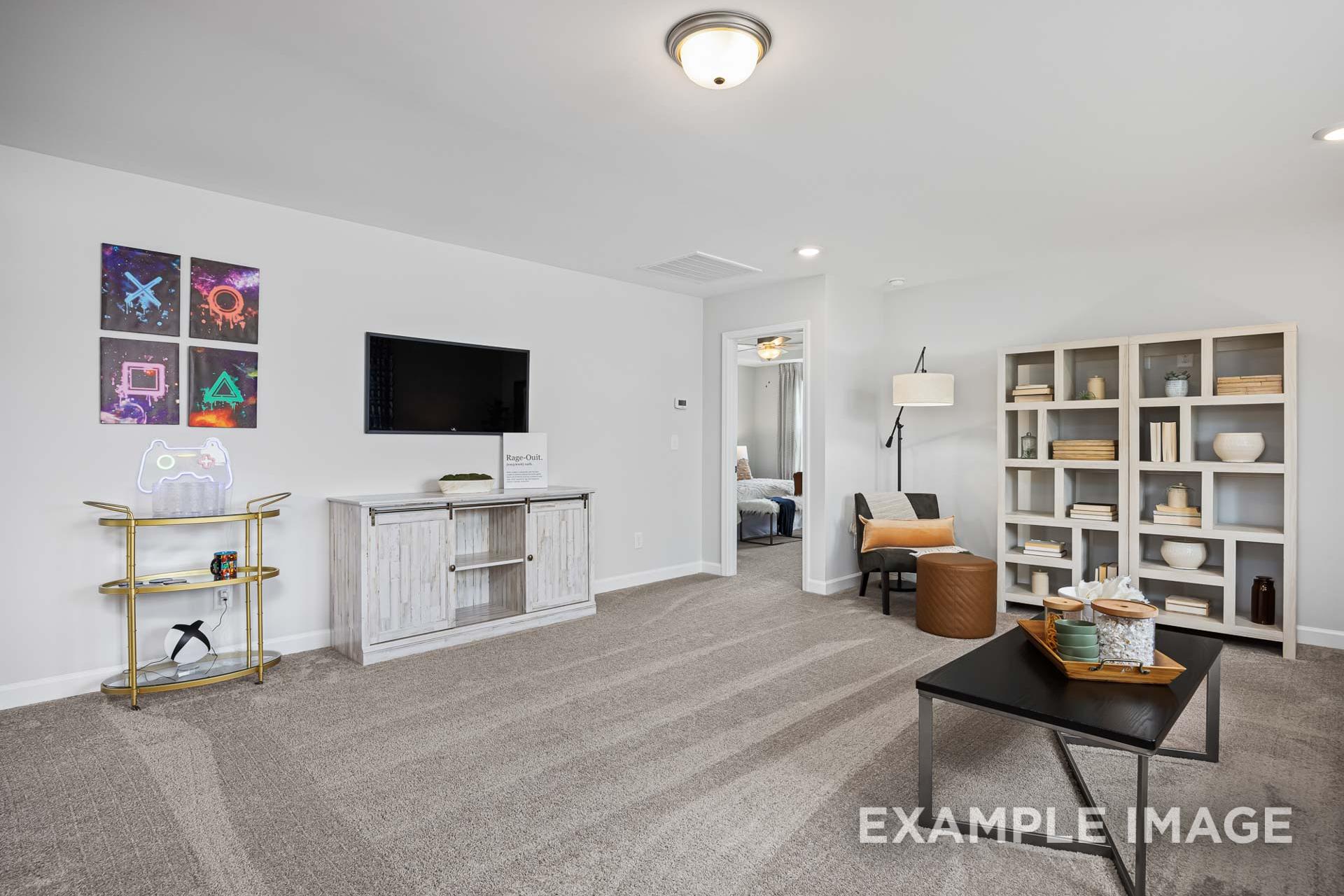 Spacious living room in The Adalynn C by Davidson Homes featuring wall-mounted TV, PlayStation decor, white bookshelves, and neutral furniture