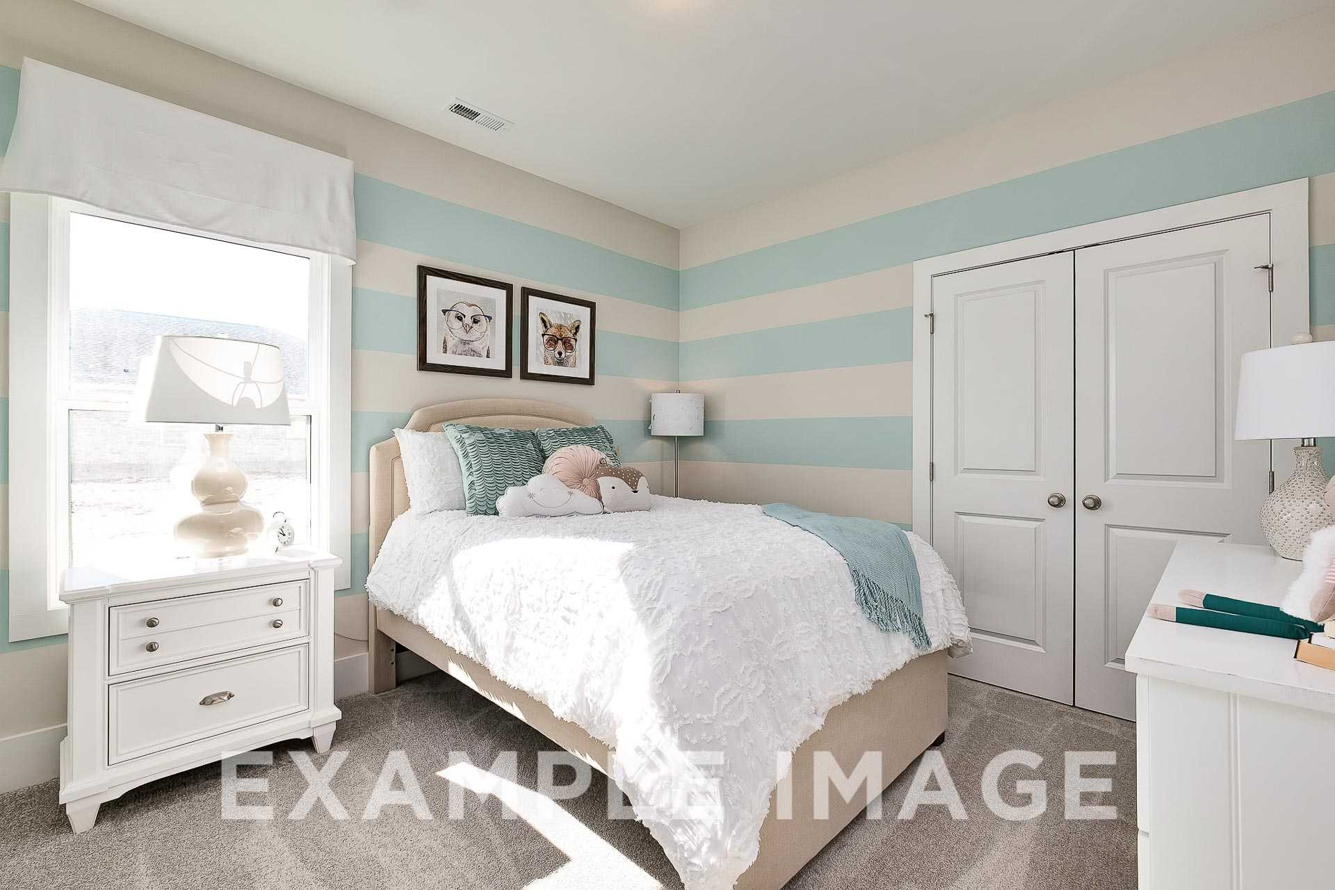 Charming girl's bedroom in The Everett B featuring blue-white striped walls, queen bed with teal throw, dog artwork, and lamps