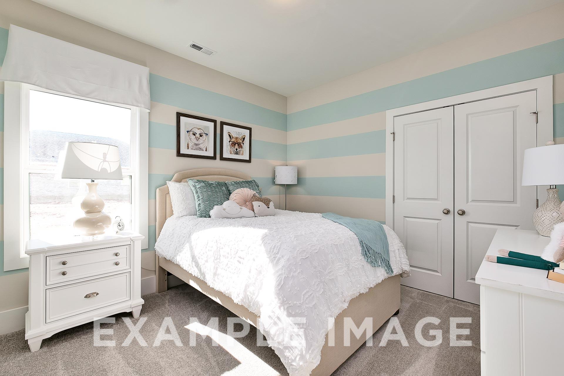 Charming girl's bedroom in The Everett B featuring blue-white striped walls, queen bed with teal throw, dog artwork, and lamps