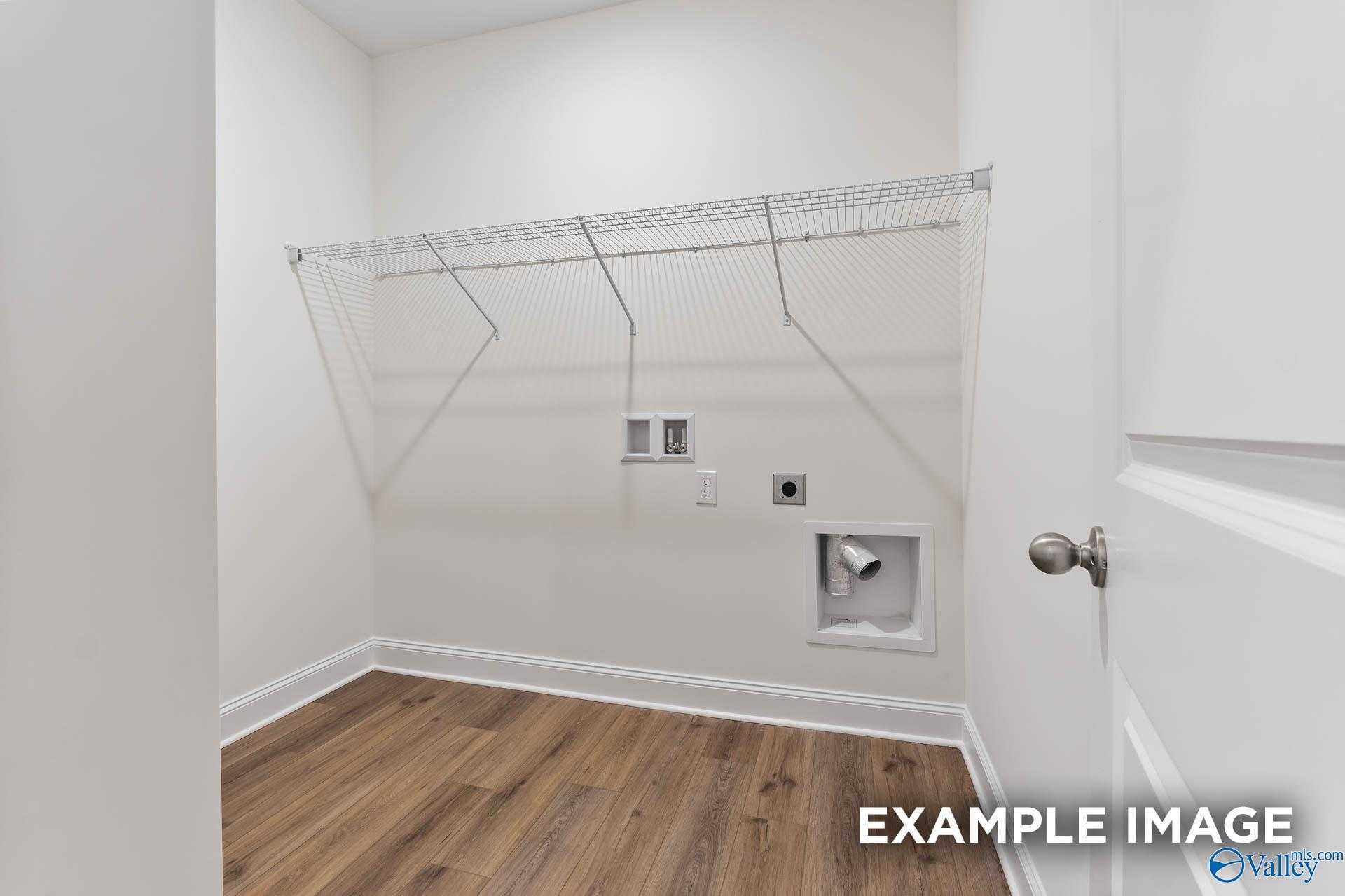 Bright laundry room with wire shelving, utility sink, and hardwood floors in Davidson Homes The Daphne V, Athens, Alabama