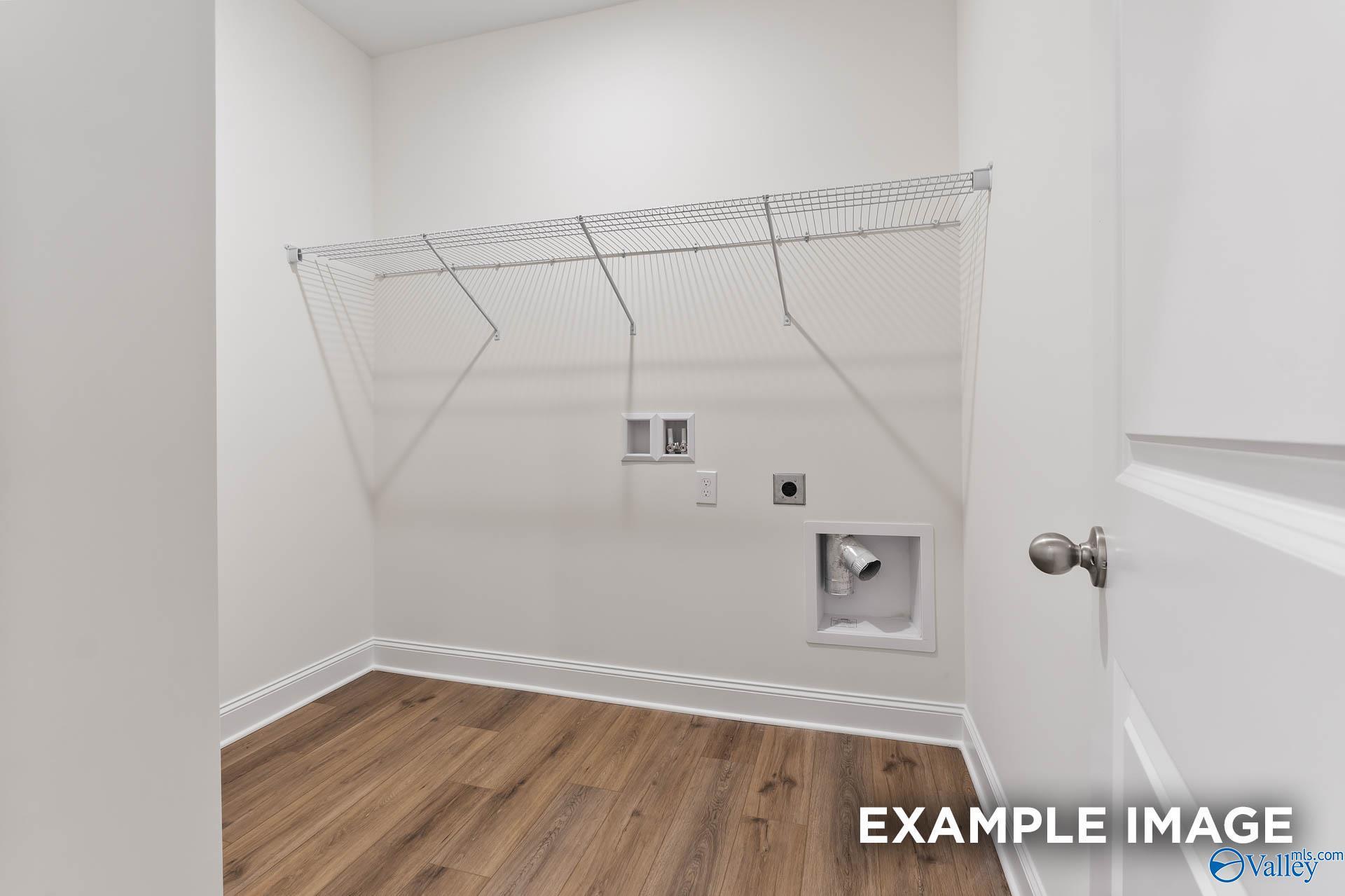 Bright laundry room with wire shelving, utility sink, and hardwood floors in Davidson Homes The Daphne V, Athens, Alabama
