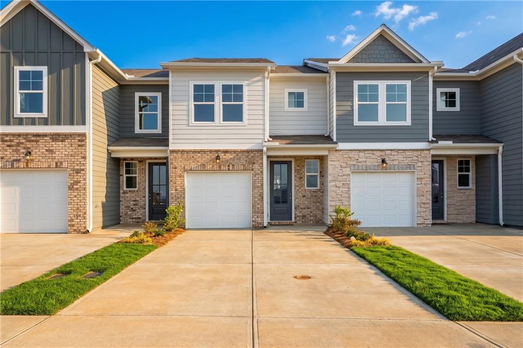 Front exterior of Davidson Homes' The Wilmington A townhome with brick and siding facade, 1-car garages in Stegall Village, Emerson, Georgia.