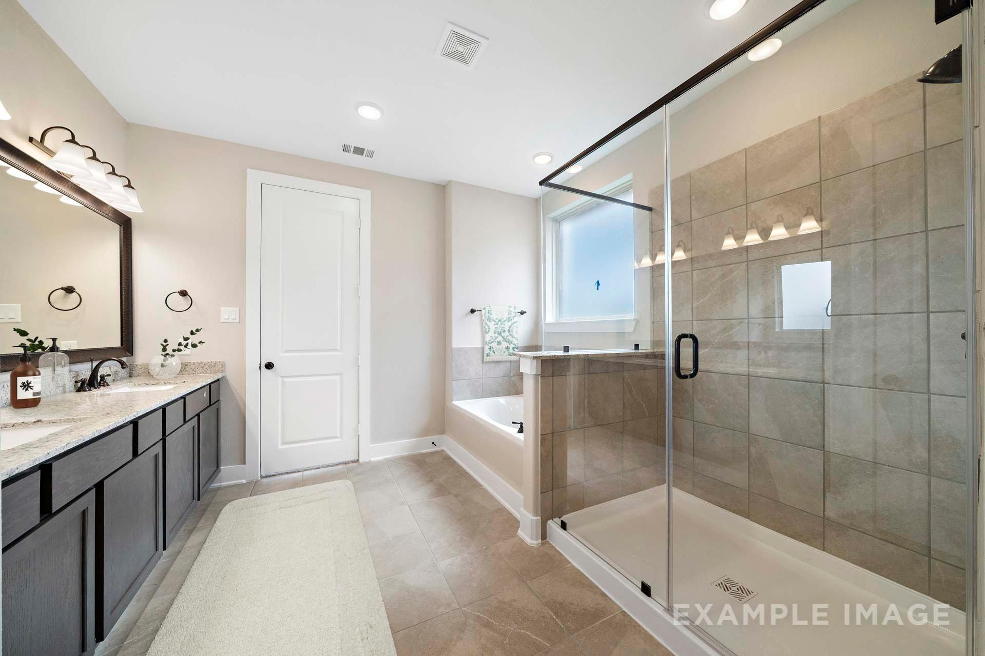 Spacious master bathroom in The Elizabeth A featuring double vanity, soaking tub, and glass-enclosed walk-in shower