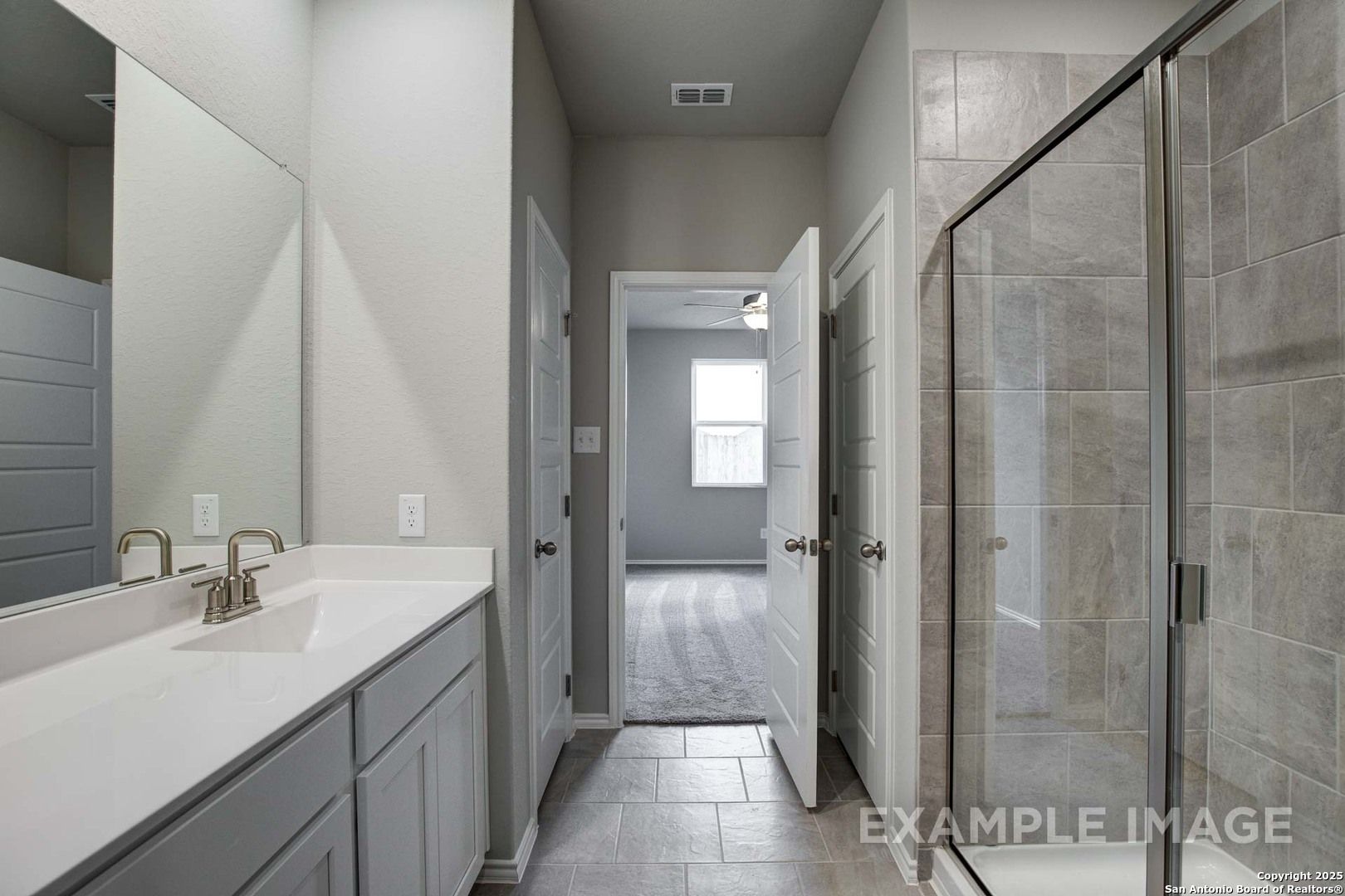 Modern master bathroom featuring double vanity, frameless glass shower, and open bedroom view in Davidson Homes The Blanco C, San Antonio