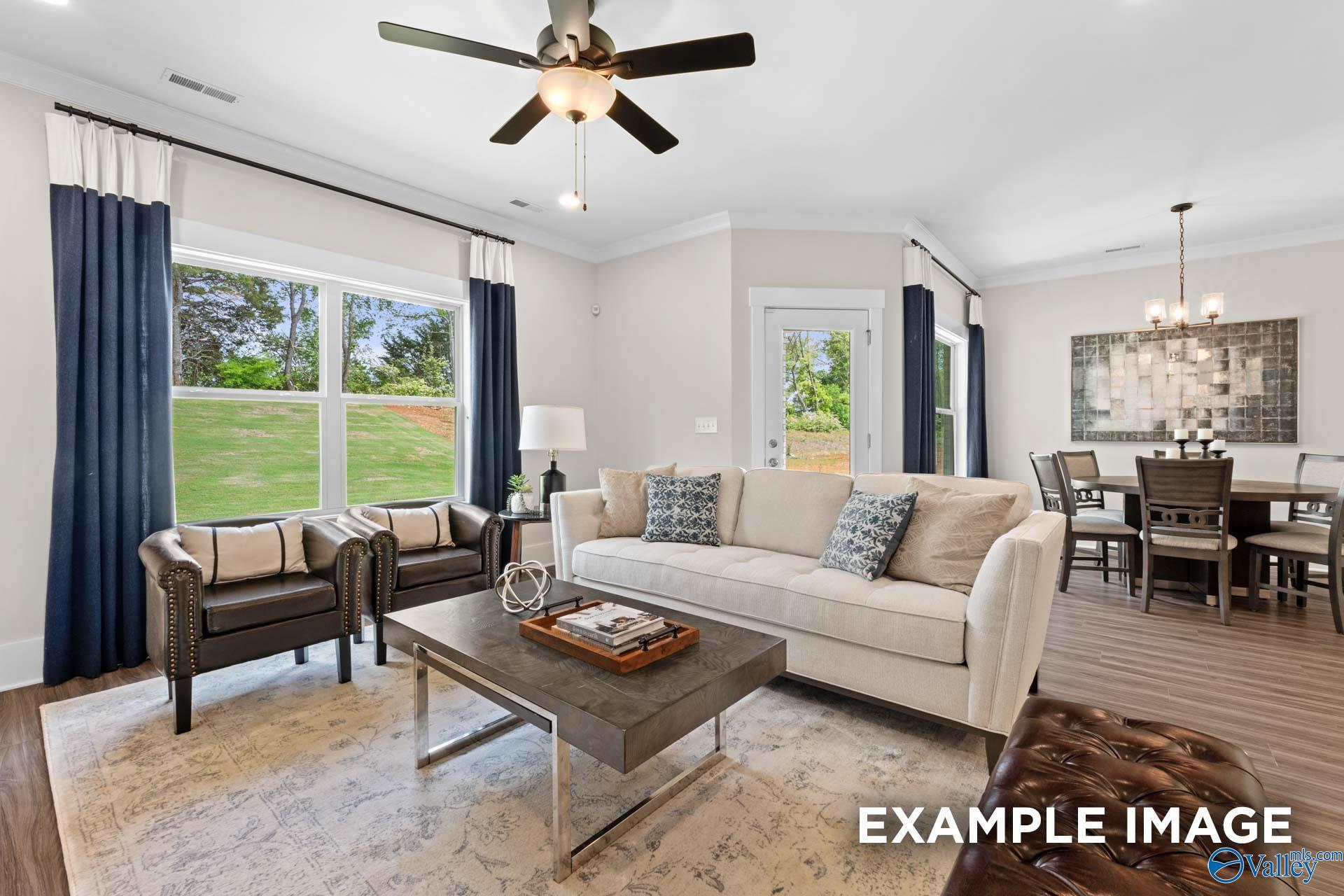 Cozy living room with beige sofa, armchairs, ceiling fan, and large windows in Davidson Homes The Daphne F, Berry Cove, New Market, Alabama