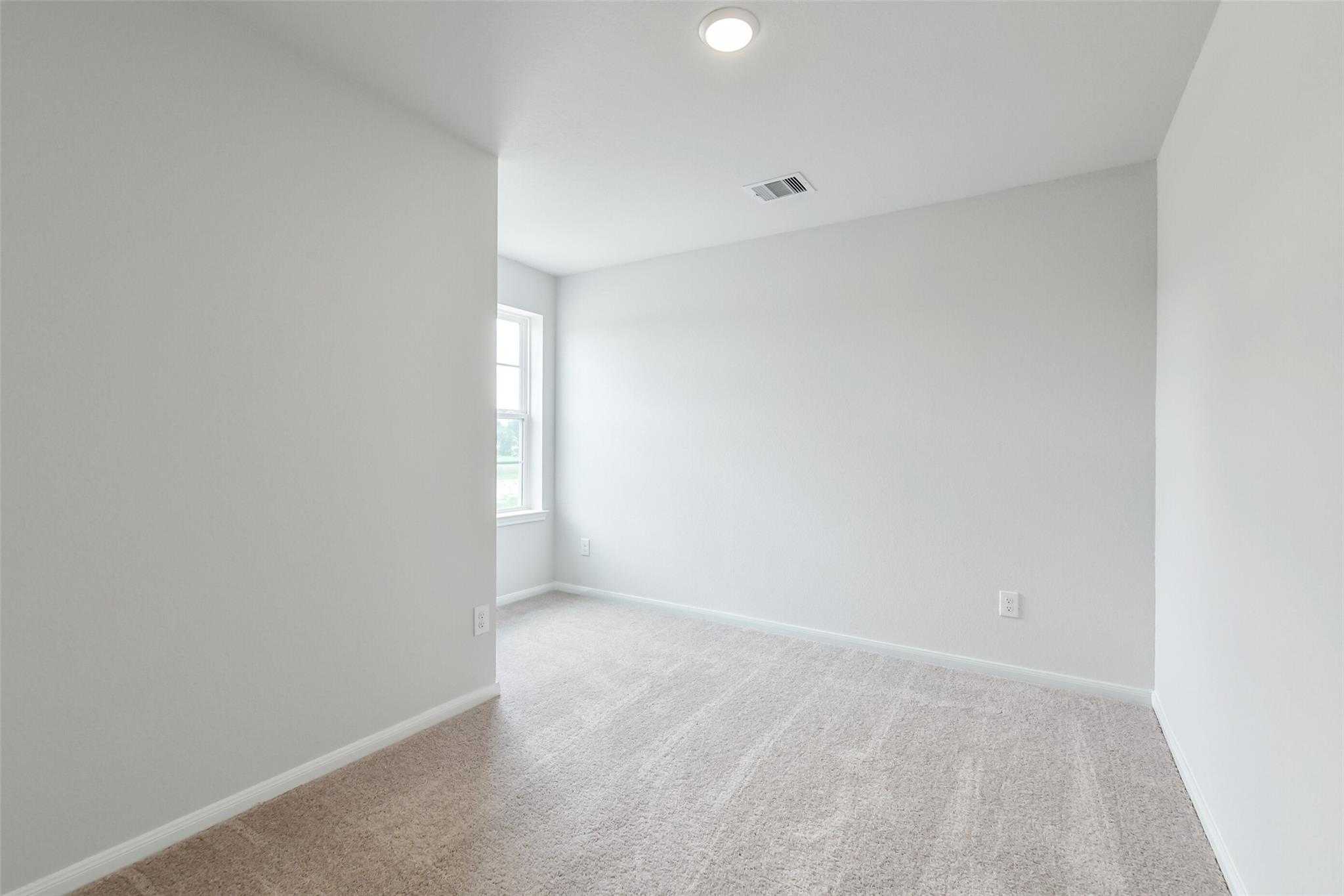 Bright secondary bedroom with neutral walls, beige carpet, large window, and recessed lighting in Davidson Homes Sabine E, Conroe TX