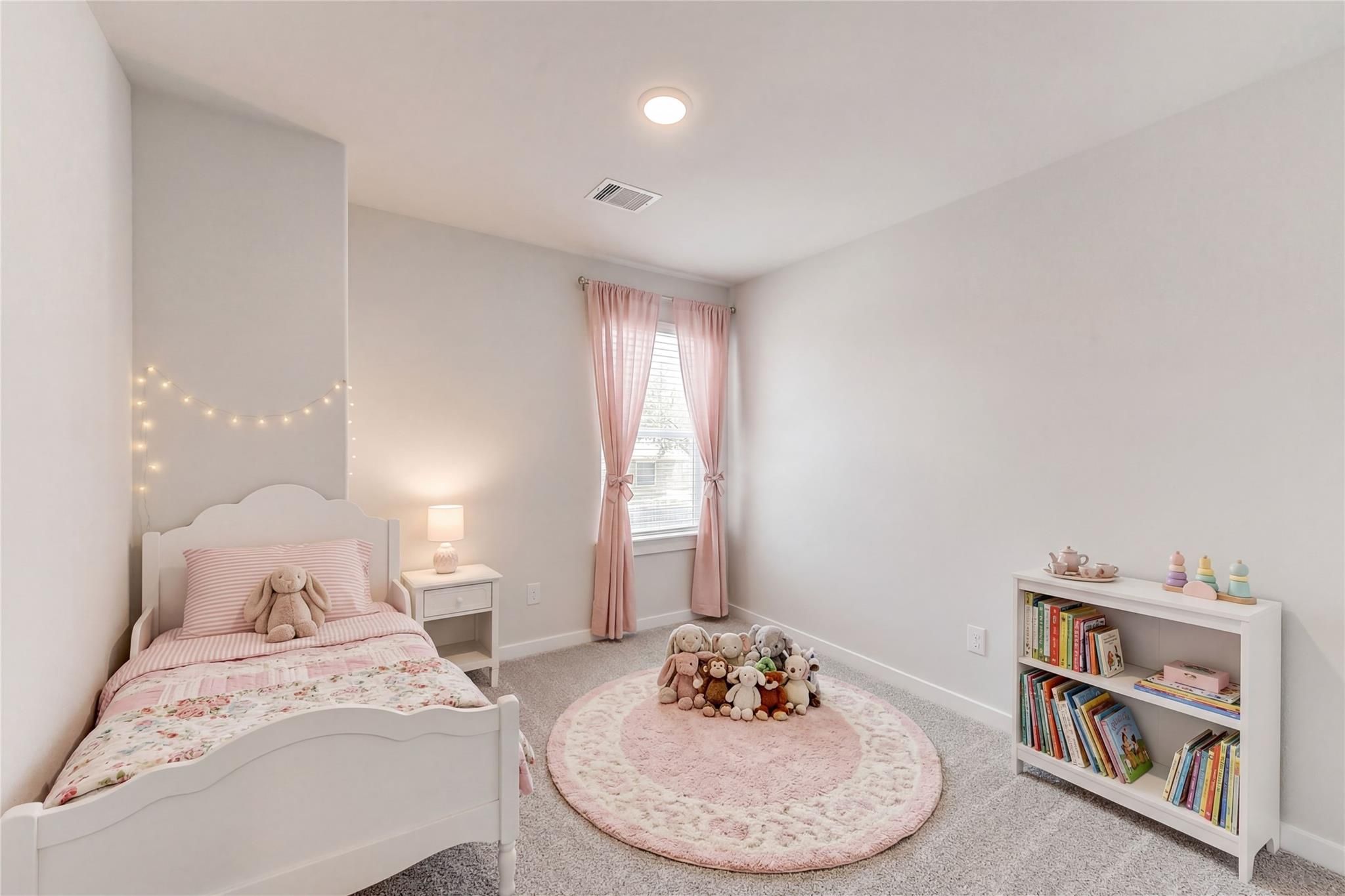 Adorable girl's bedroom with pink floral twin bed, stuffed animals, bookshelves in Davidson Homes The Brazos E, Magnolia, Texas