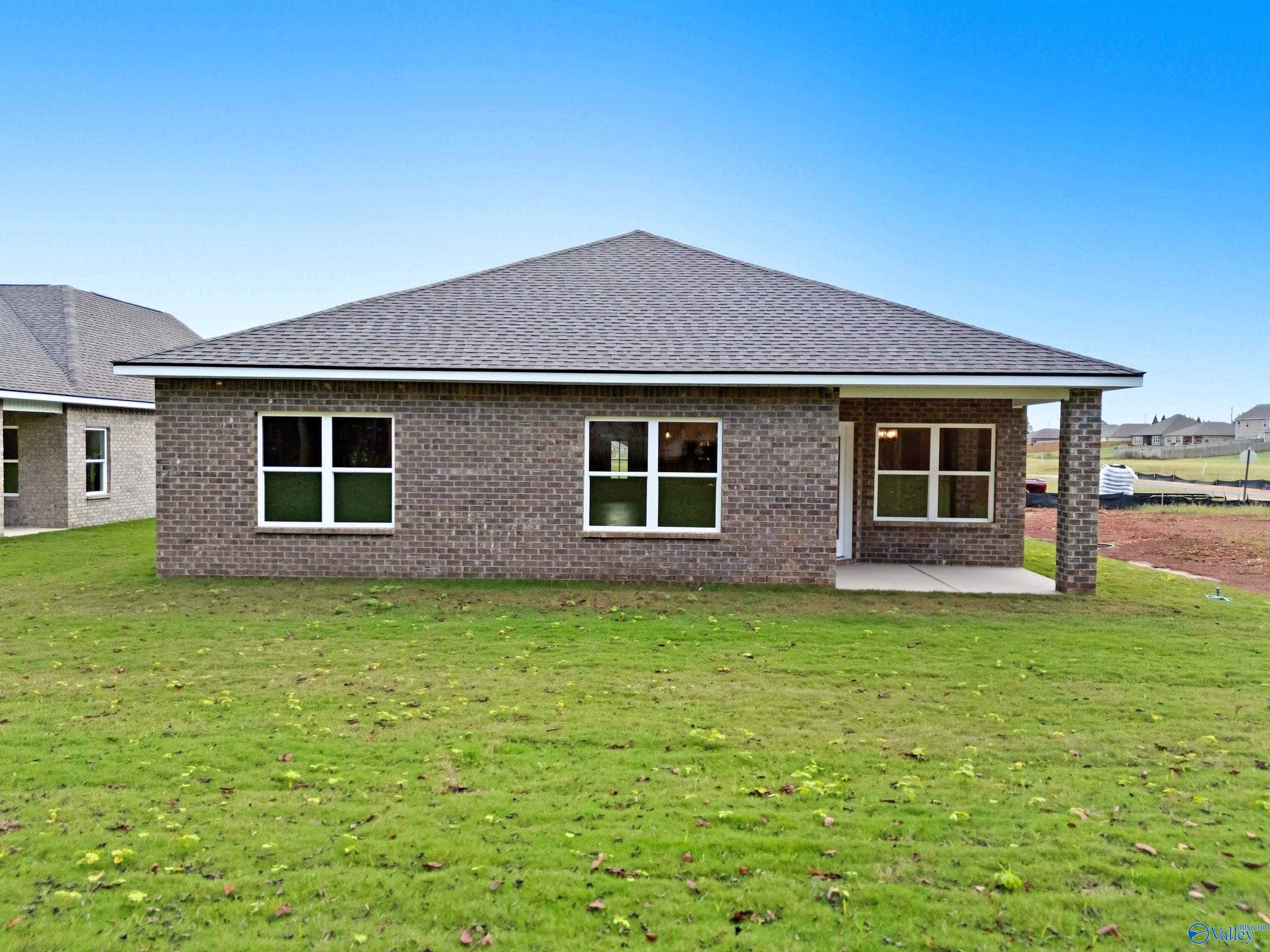 Modern brick single-story 4-bedroom home with gable roof, covered porch, and lush green lawn in Lynn Meadows, Meridianville, Alabama