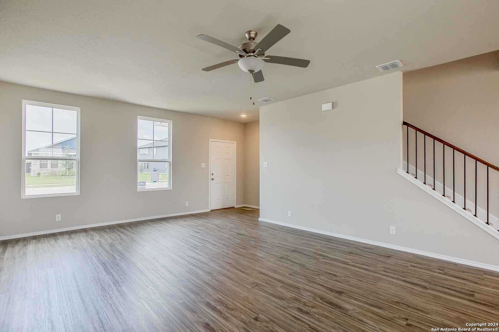 Spacious open entry with hardwood floors, ceiling fan, large windows, and staircase in Davidson Homes The Murray H, Seguin Texas