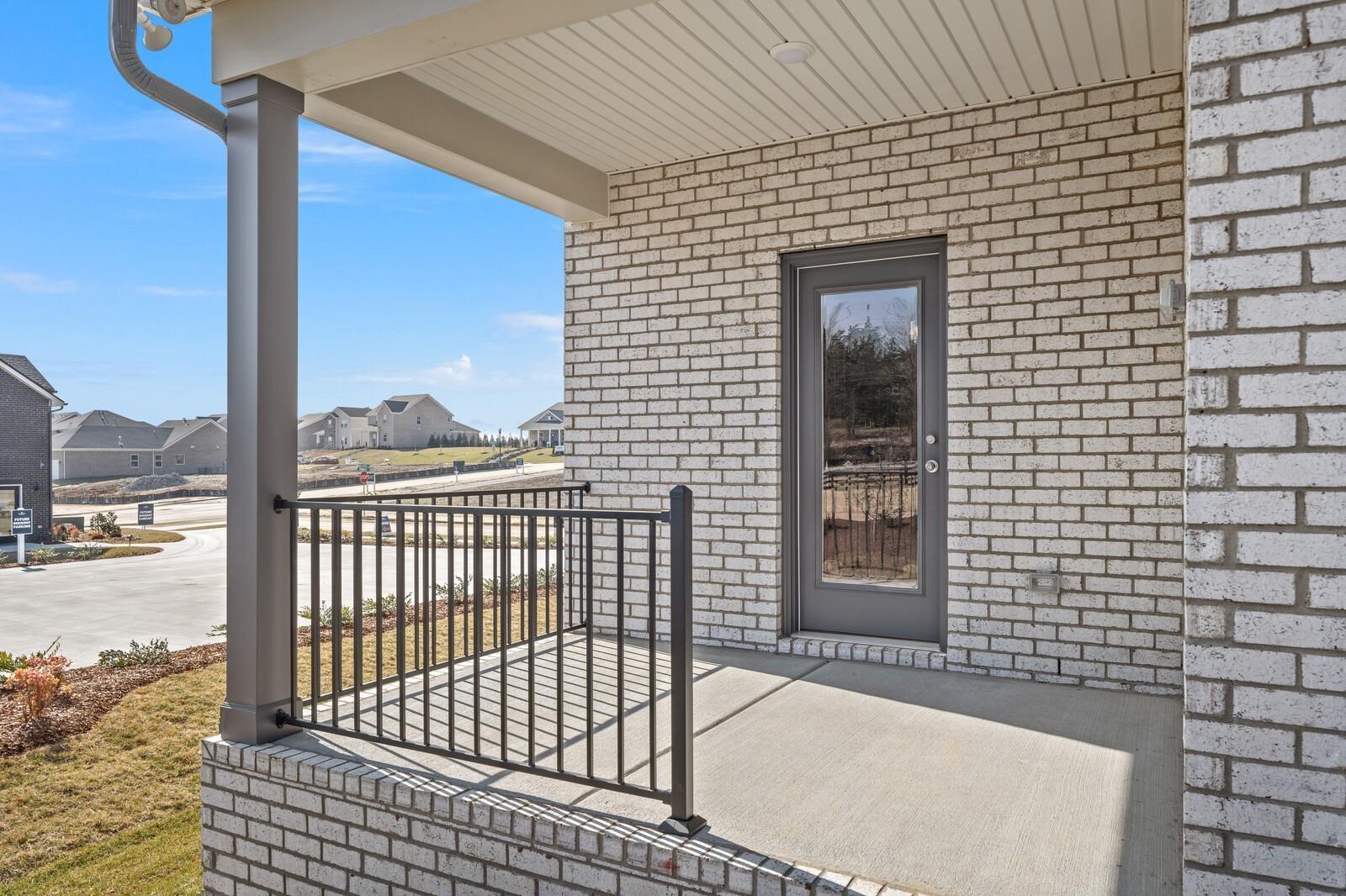 Inviting brick front porch with metal railing and glass door on Davidson Homes The Ash C in Benders Cove, Mt. Juliet, TN