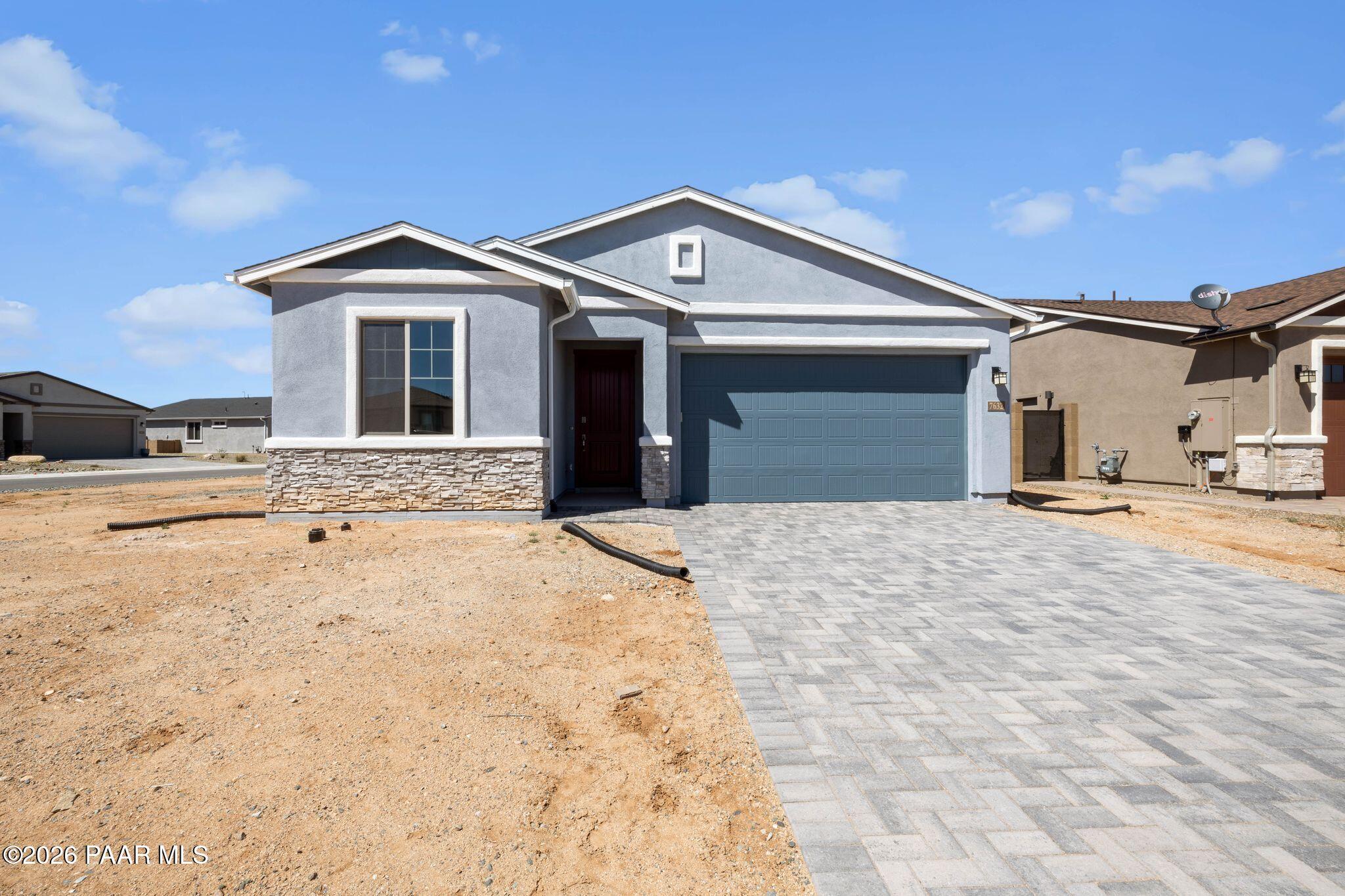 Modern gray single-story home with stone accents, large windows, and 3-car garage in North Ridge at Pronghorn Ranch, Prescott Valley, Arizona