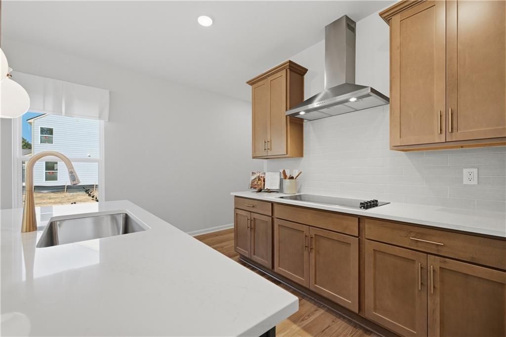 Modern kitchen with white quartz island, stainless sink, and wood cabinets in Davidson Homes The Sinclair B, Cartersville, Georgia