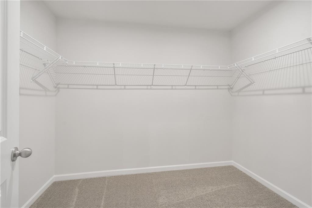 Spacious walk-in closet with wire shelving and beige carpet in master suite of Davidson Homes The Cary A, Kennesaw, GA