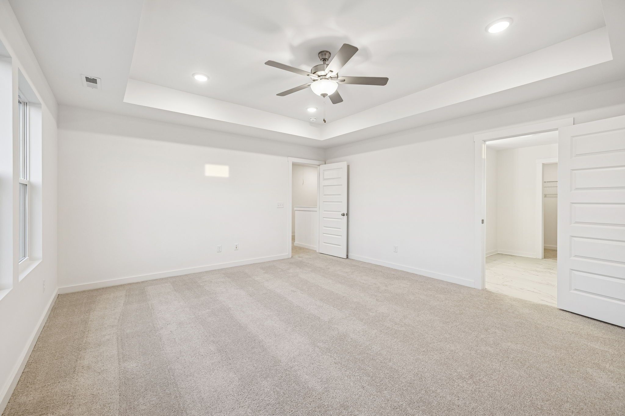 Spacious master bedroom with tray ceiling, ceiling fan, walk-in closet, and en-suite bath in Davidson Homes The Willow, Calista Farms