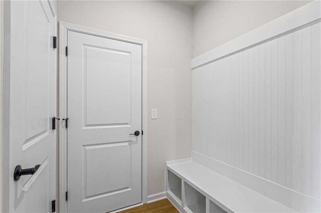 White shiplap mudroom with built-in bench, storage cubbies, and double doors in Davidson Homes The Edison A, Loganville, Georgia
