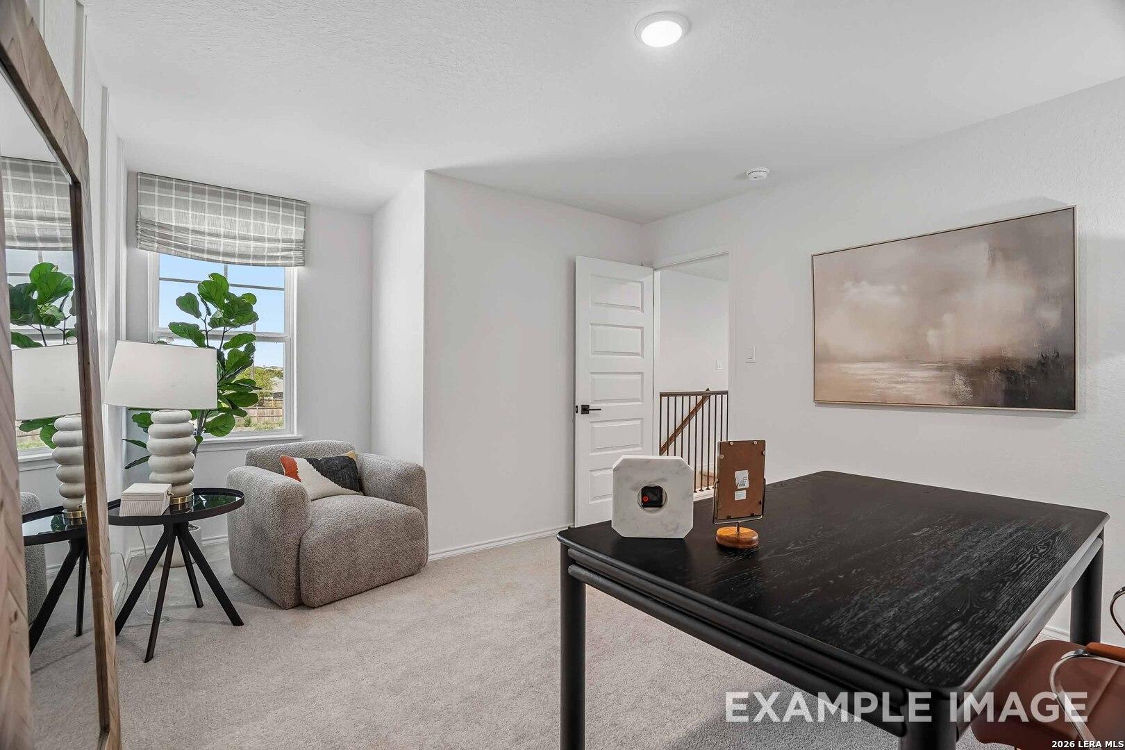 Bright upstairs bedroom with sitting area, accent chair, and natural light in Davidson Homes The Pinecrest F, Morgan Meadows San Antonio