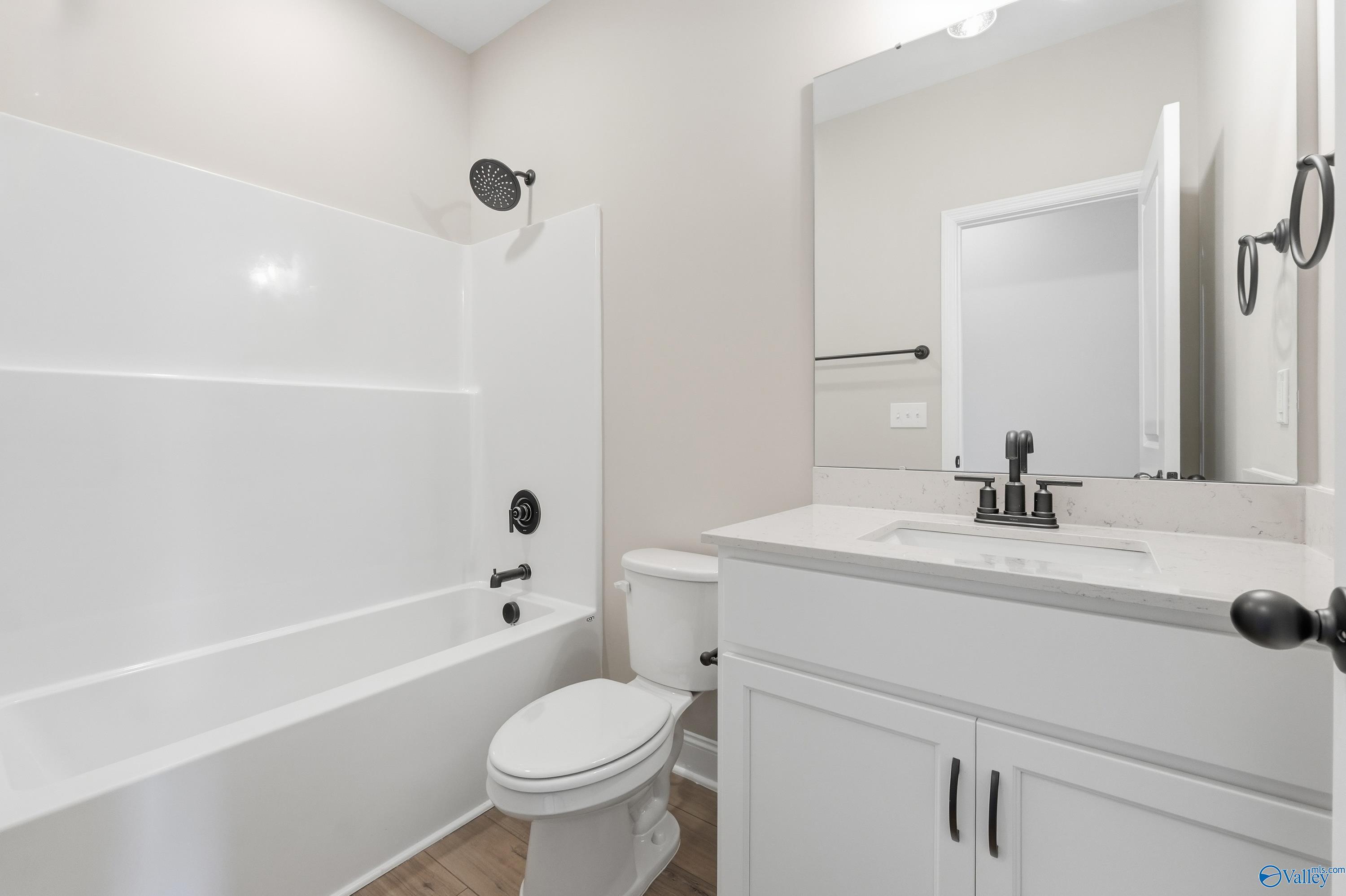 Bright bathroom with white tub-shower combo, vanity sink, toilet in Davidson Homes The Rockford C, Athens, Alabama