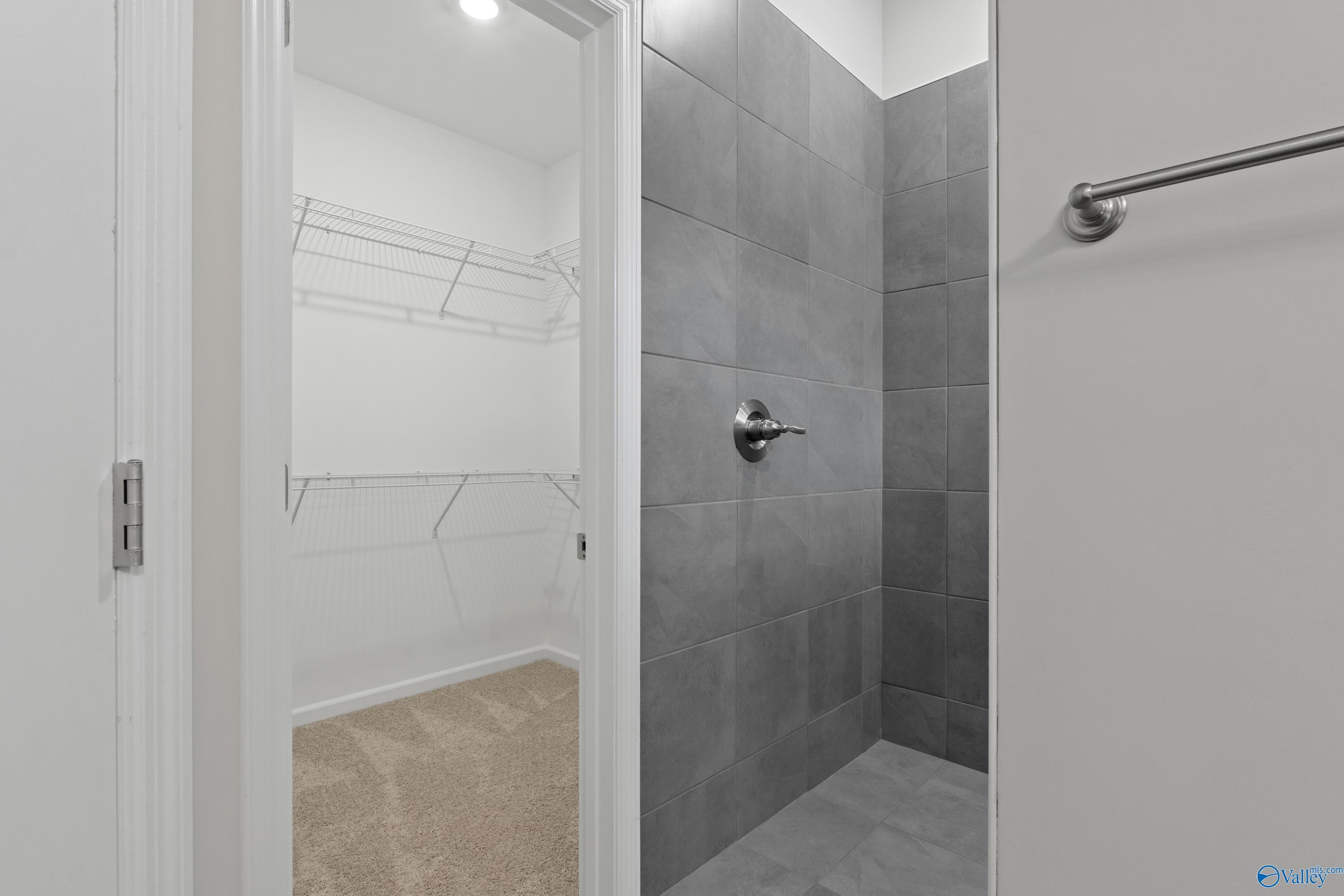 Modern master bath with gray tiled walk-in shower and adjacent closet in Davidson Homes The Dorado, Athens AL