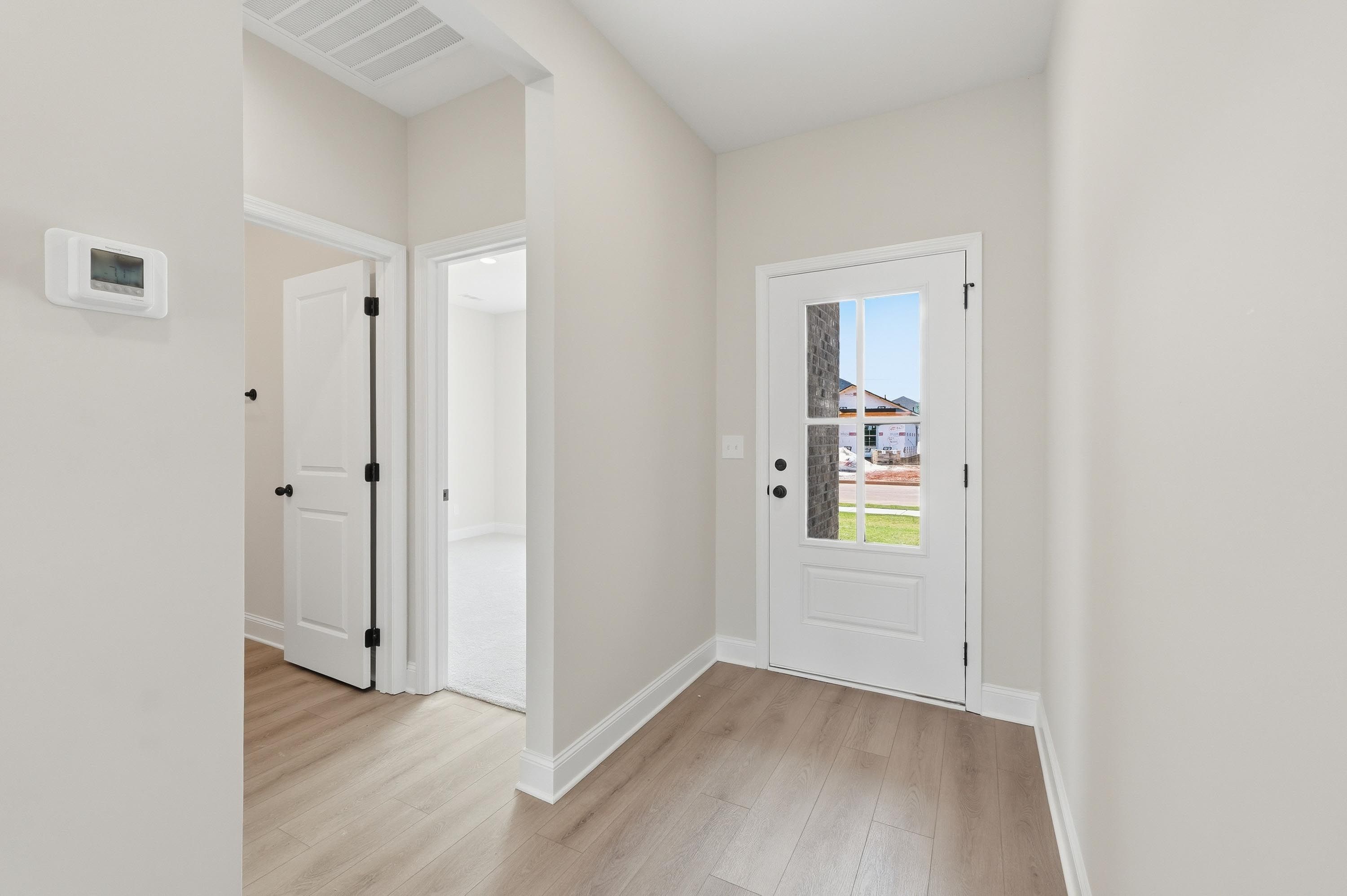 Bright entryway of The Glen A featuring light wood-look flooring, white doors, and views of the Josephine, Texas community.