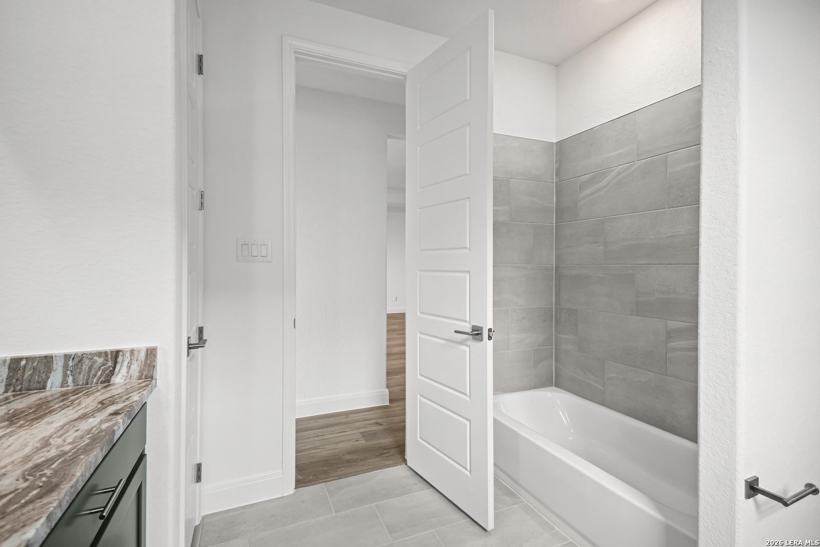 Modern bathroom with gray tile shower surround in The Lanier G floor plan at The Reserve at Potranco Oaks, Castroville, TX.