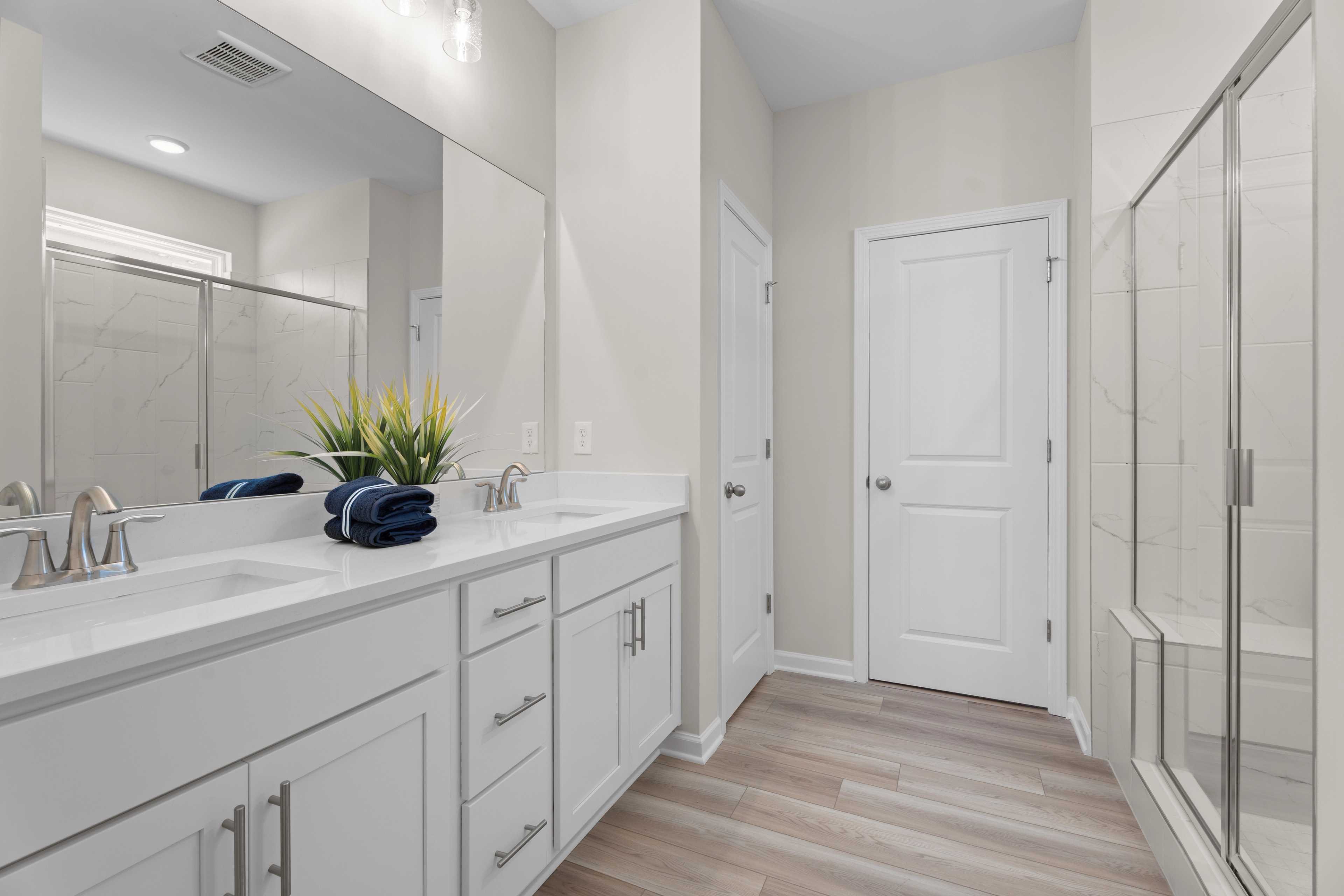 Owners bathroom with dual sinks and shower with bench