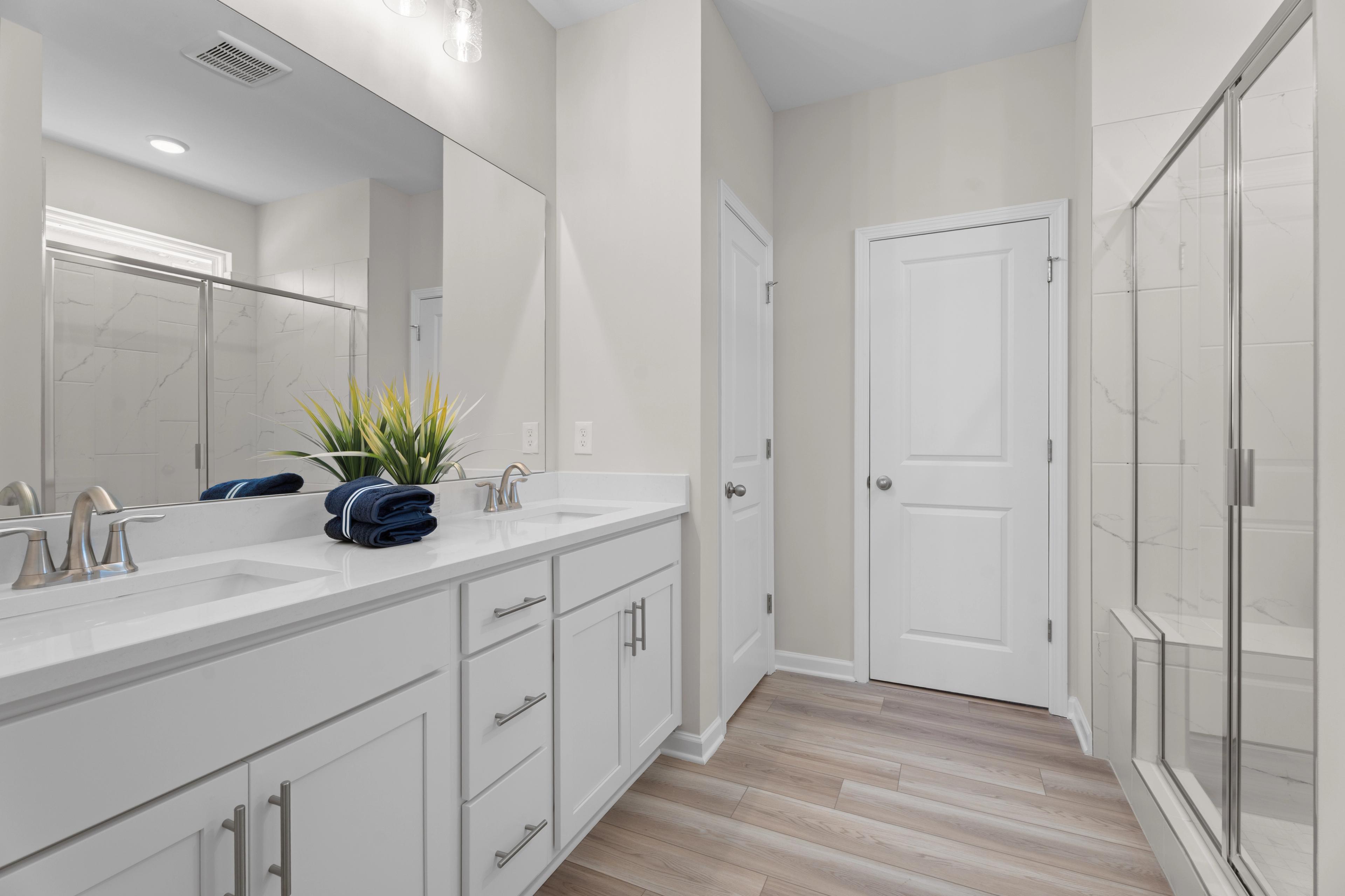 Owners bathroom with dual sinks and shower with bench