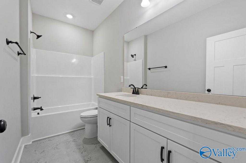 Modern bathroom with white subway tile shower, soaking tub, double quartz vanity, white cabinets in Evermore Homes The Oxford, Owens Cross Roads, AL