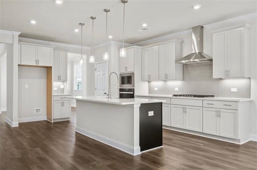 Modern kitchen with white cabinets, center island, and stainless steel appliances in The Ash C at Wehunt Meadows, Hoschton