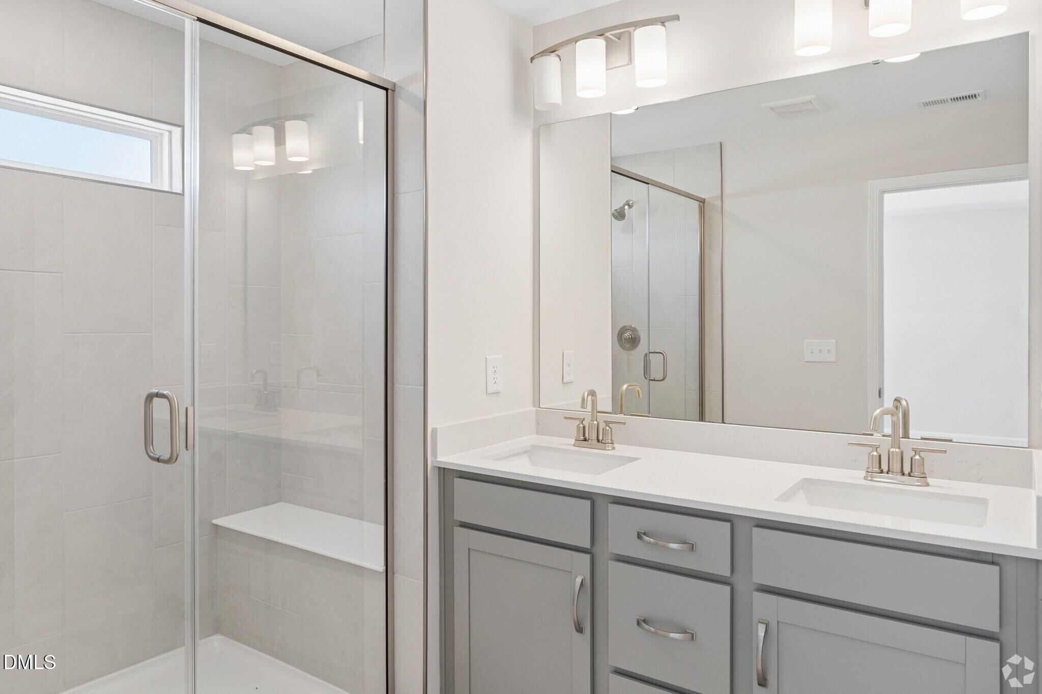 Modern bathroom with dual vanity, glass walk-in shower, and gray cabinetry in Davidson Homes The Avery, Knightdale, NC