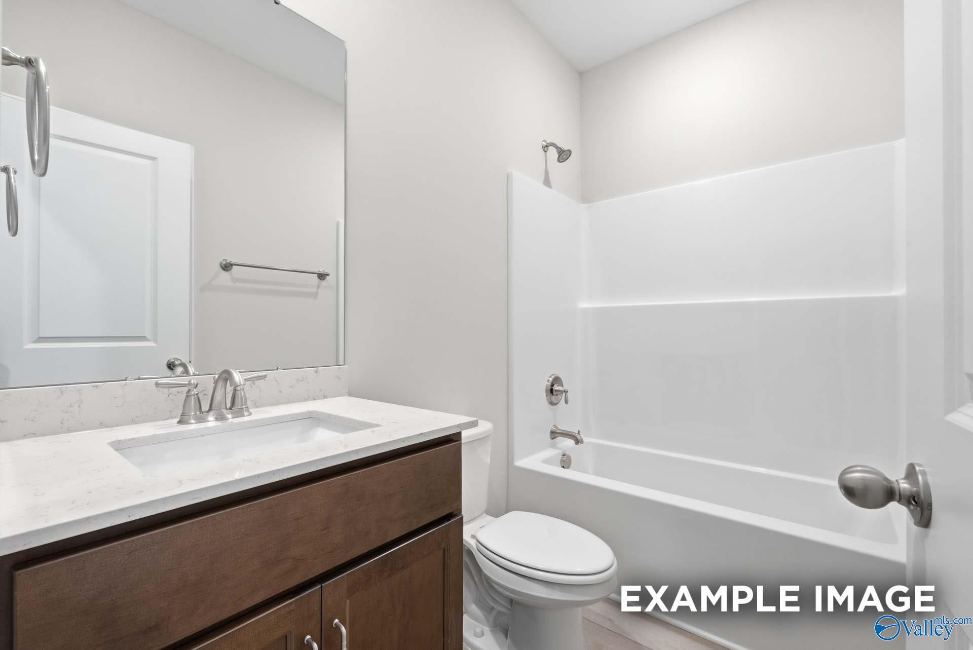 Modern bathroom with white tub-shower combo, quartz vanity, and chrome fixtures in Davidson Homes The Harrison C, Madison AL