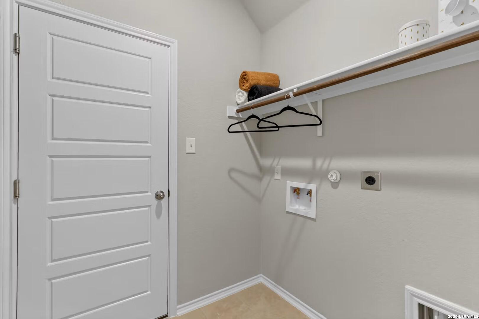 Laundry room with washer and dryer hookups and overhead shelving in The Summit B floor plan, Morgan Meadows, San Antonio.