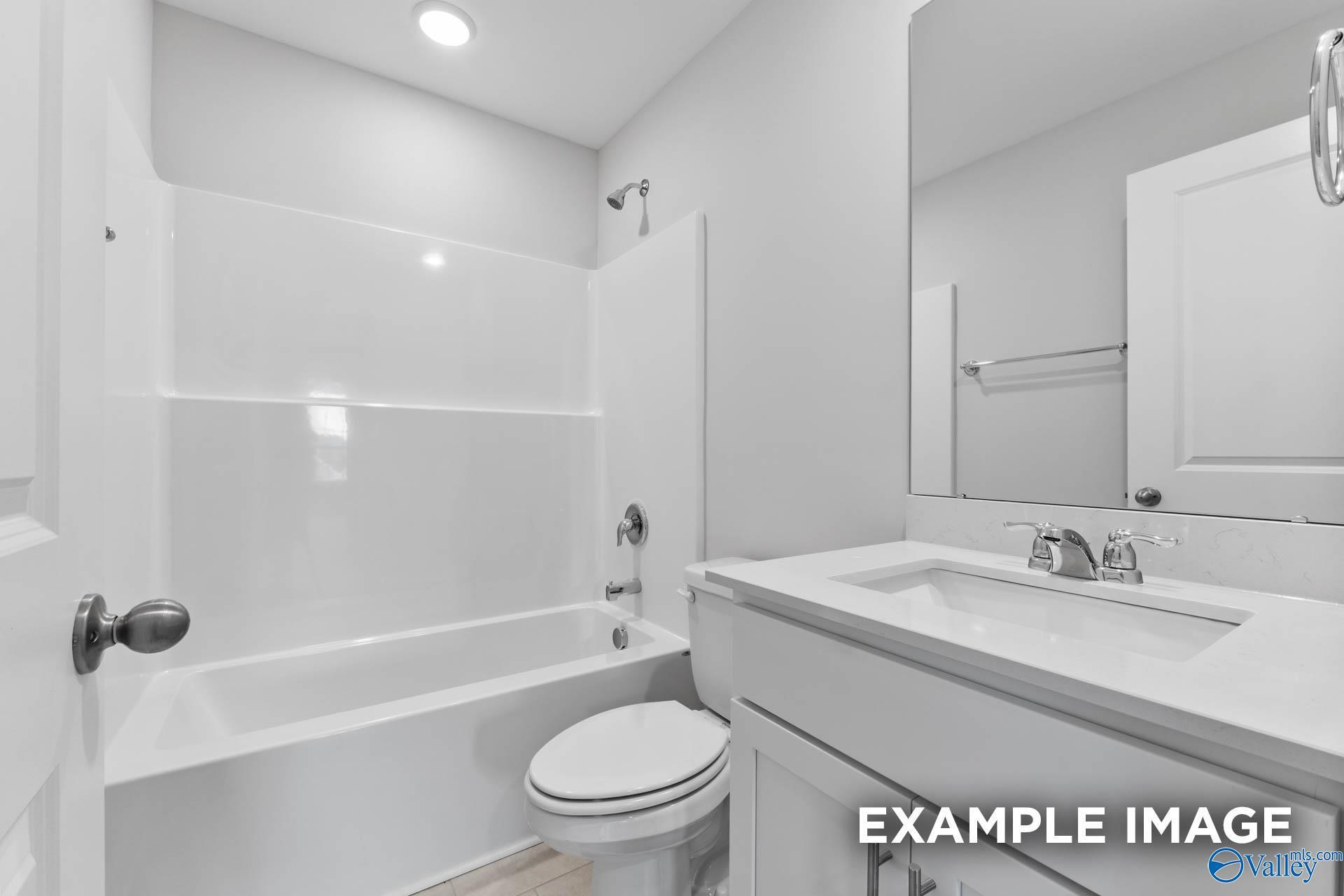 Modern bathroom with white vanity, tub-shower combo, and large mirror in The Madison D home at Evergreen Mill, Madison, AL.