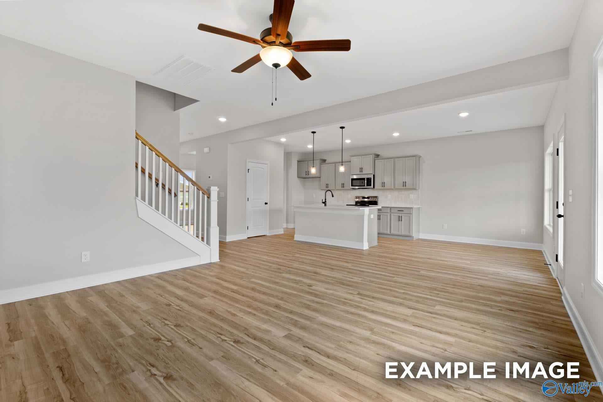 Open-concept living room and kitchen with wood-look flooring in The Shelby B floor plan, Jaguar Hills, Huntsville, Alabama.