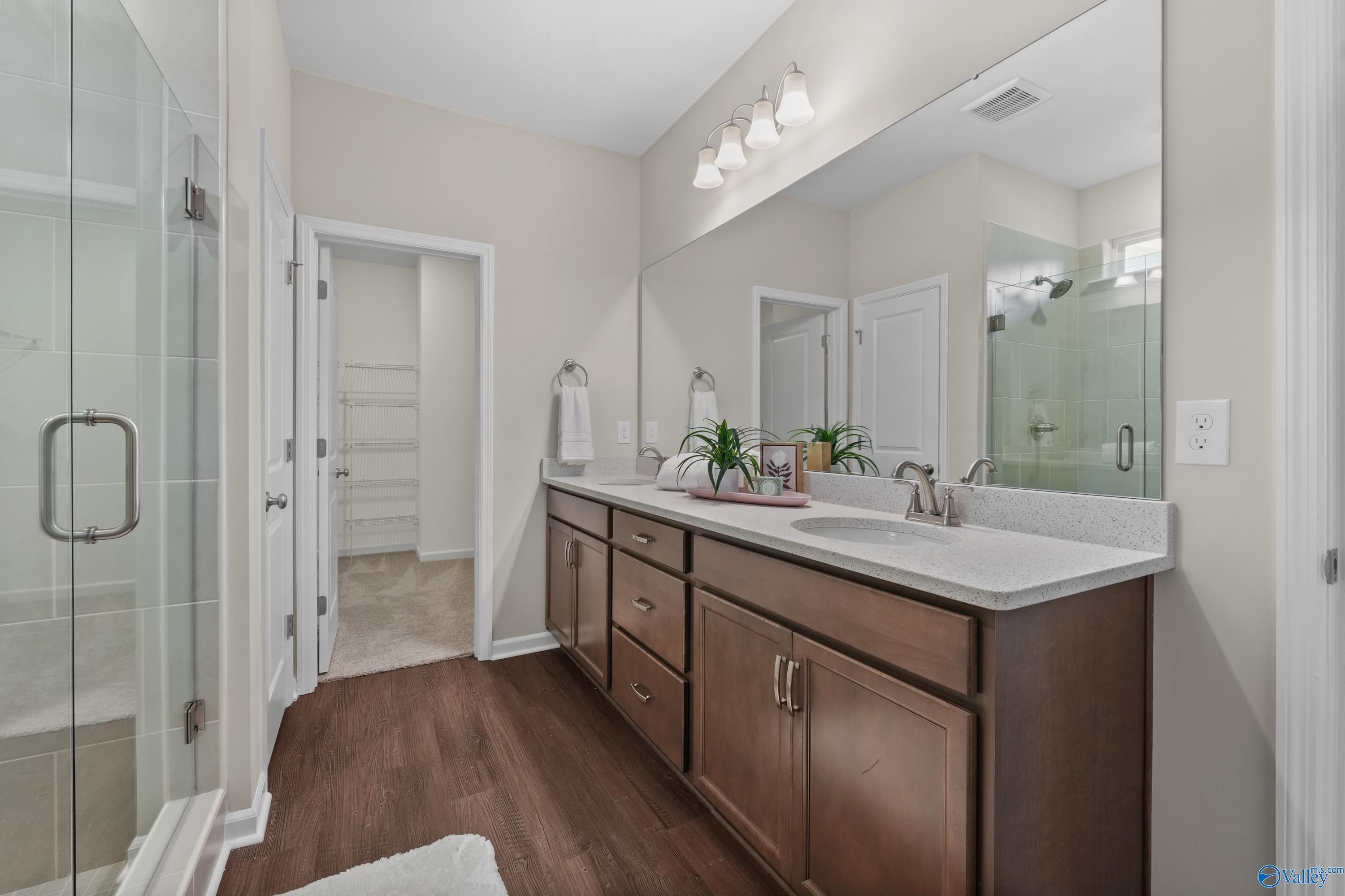 Elegant master bathroom featuring double vanity, frameless glass shower, and linen closet in Davidson Homes The Stella, Hazel Green, AL