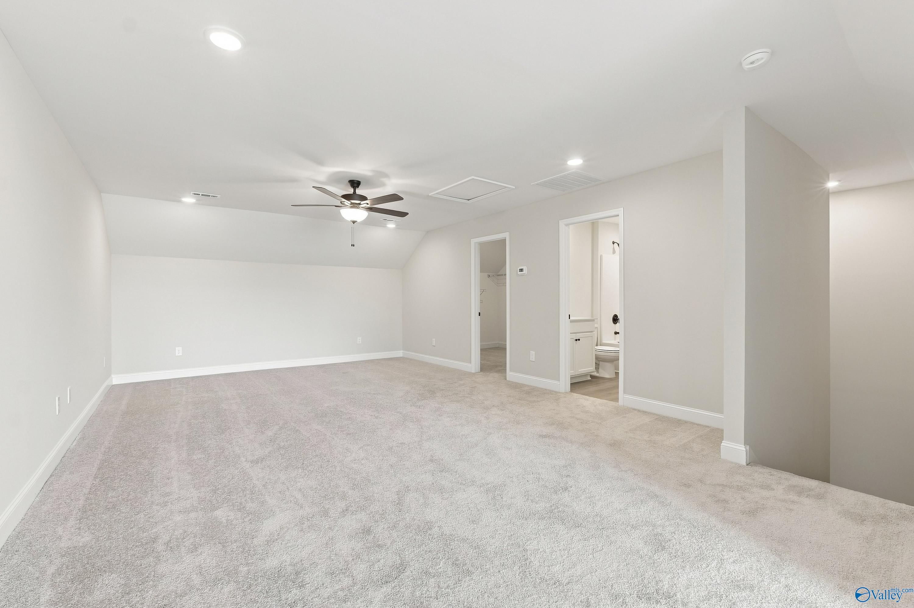 Spacious carpeted bonus room in The Rockford B floor plan at Kendall Downs in Toney, Alabama.