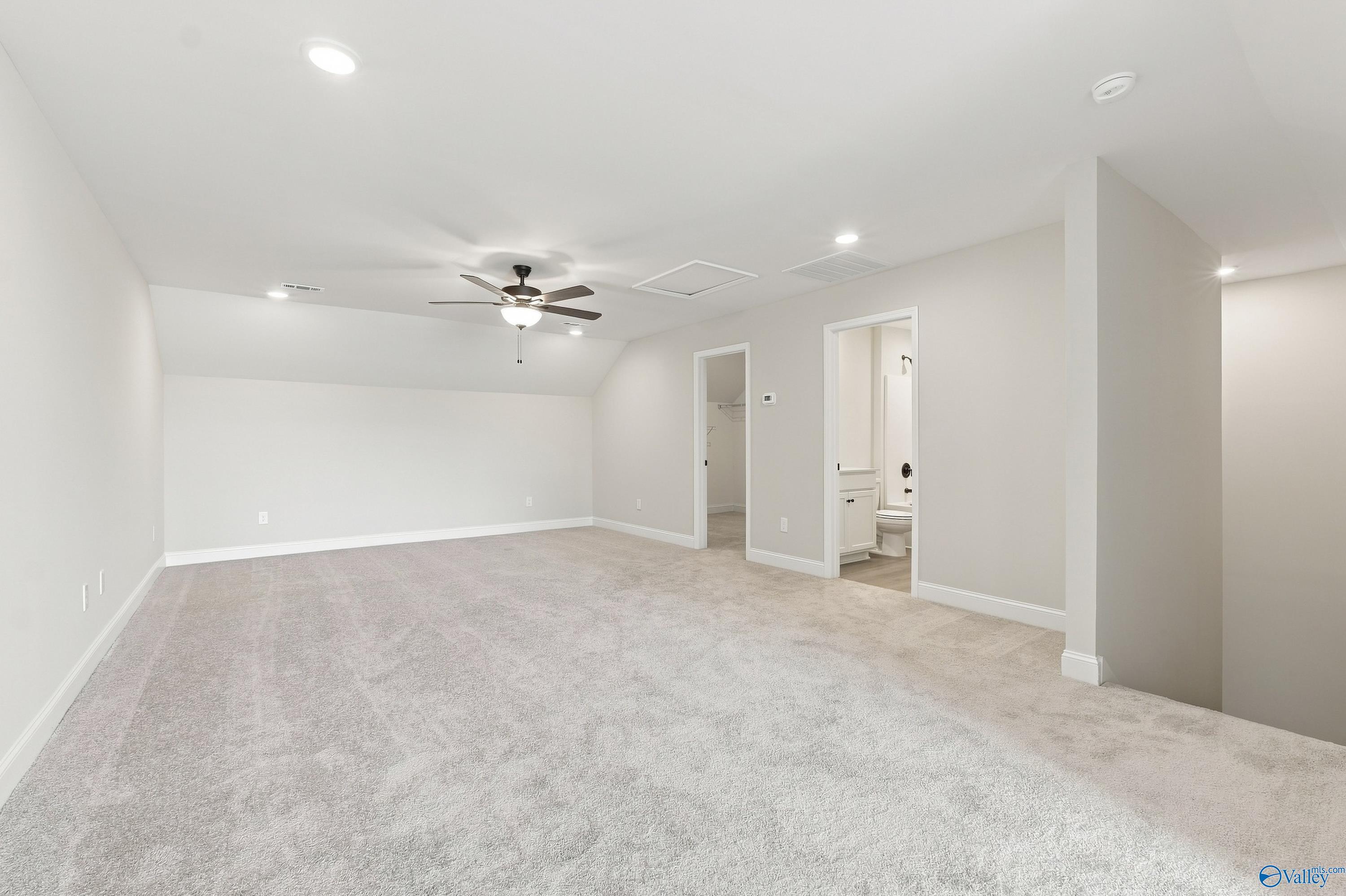 Spacious carpeted bonus room in The Rockford B floor plan at Kendall Downs in Toney, Alabama.
