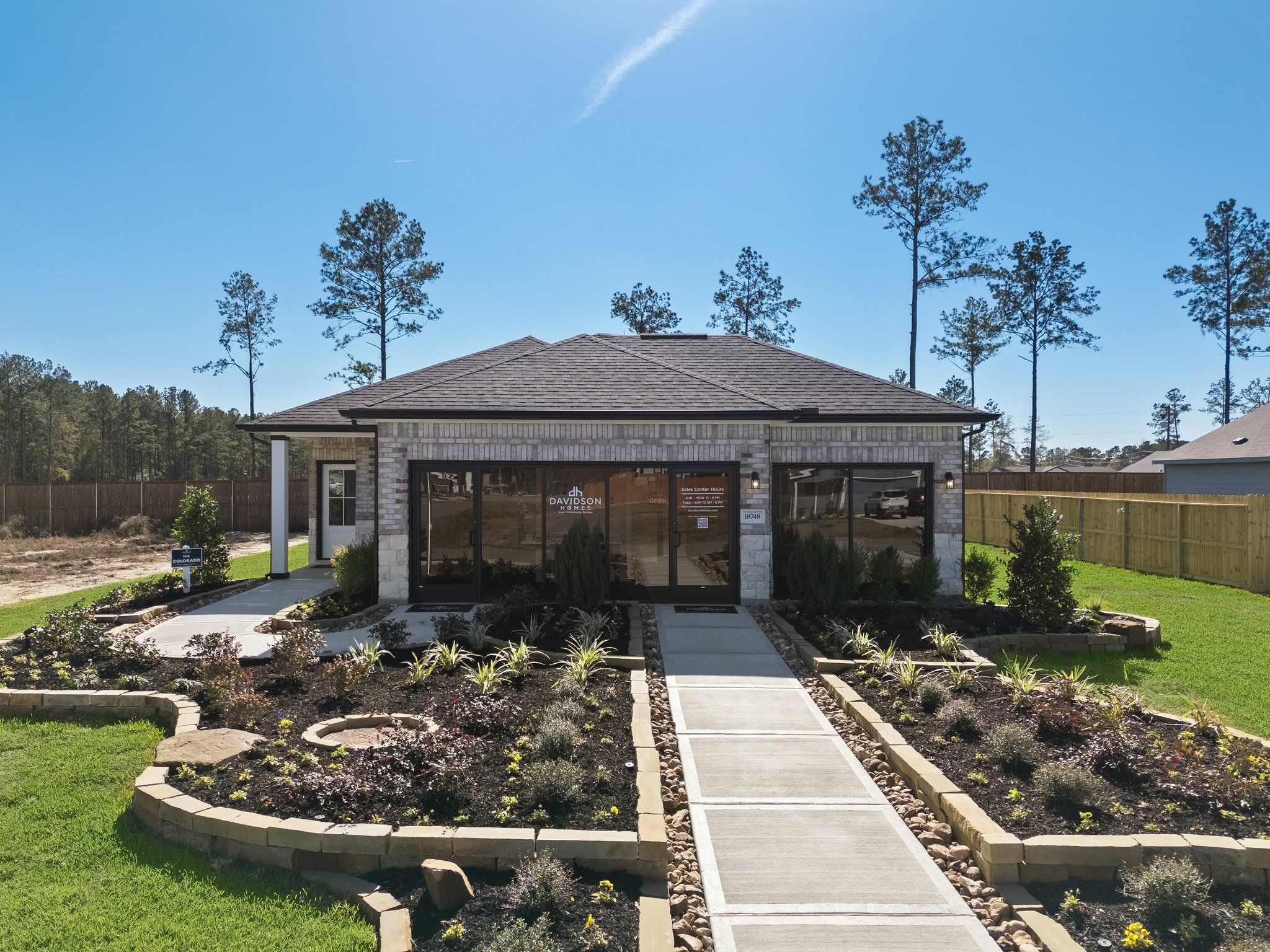 Stone and brick model home exterior at Spring Branch Crossing in Conroe Texas with landscaped gardens and walkway